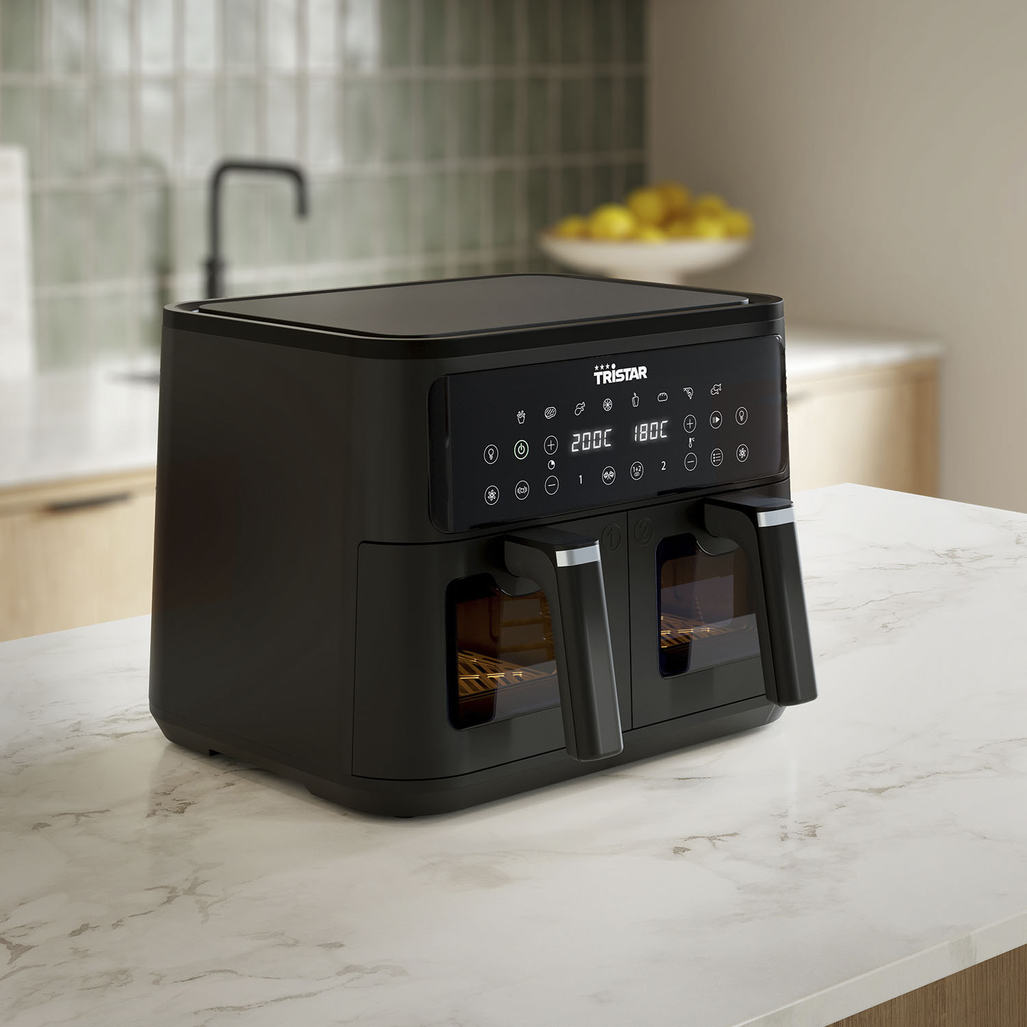 Black Tristar air fryer on a white marble countertop with fries and chicken nuggets inside.