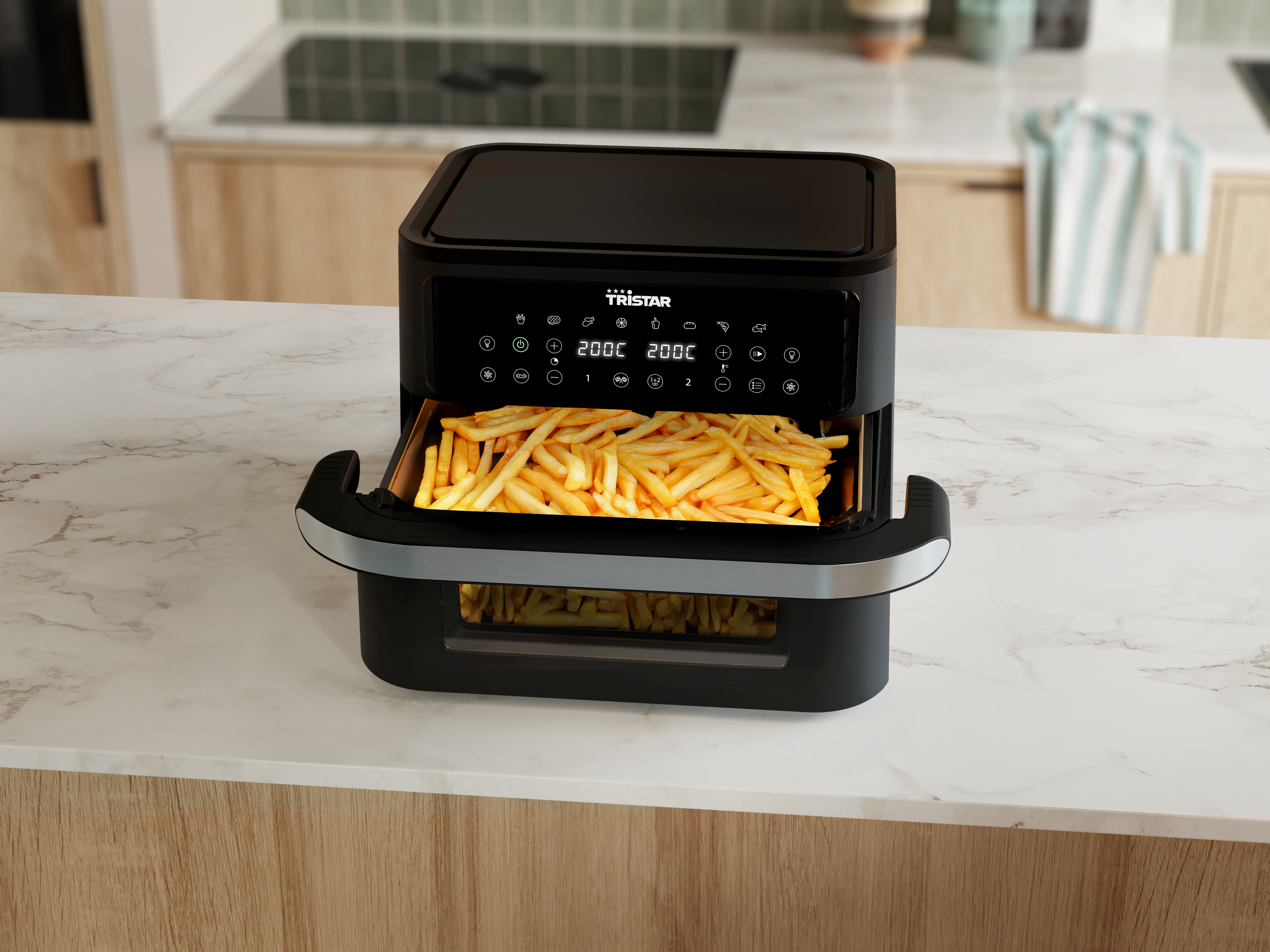 Una friggitrice ad aria con patatine fritte all'interno, su un piano di lavoro bianco. Sfondo della cucina.