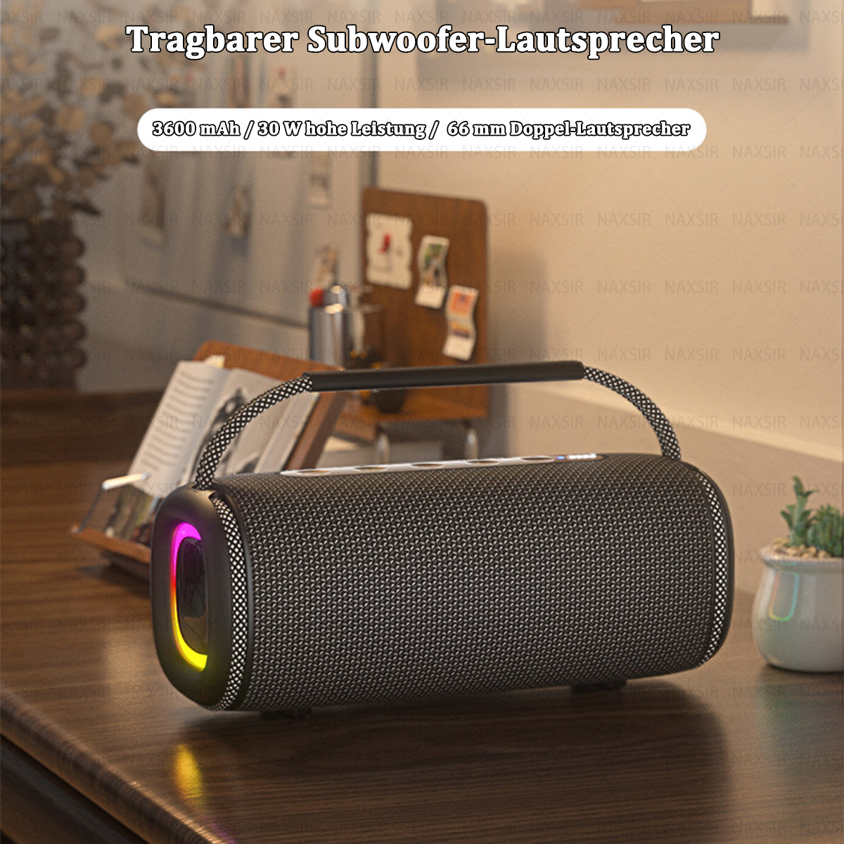 Schwarzer Lautsprecher mit Griff. Der Lautsprecher hat Lichter. Eine Pflanze und einige Gegenstände sind im Hintergrund.
