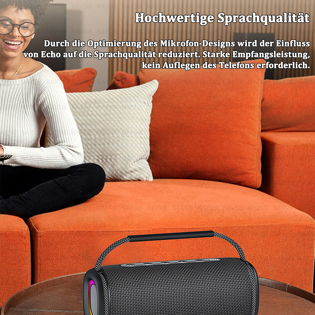 Frau sitzt auf einem orangefarbenen Sofa und benutzt einen Lautsprecher. Der Lautsprecher steht auf einem Tisch. Der Hintergrund ist verschwommen.