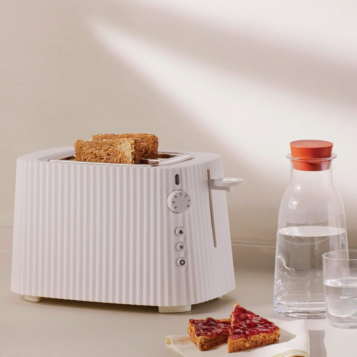 Ein weiß-beiger gestreifter Toaster. Zwei Brotscheiben sind getoastet. Es gibt eine Wasserflasche.