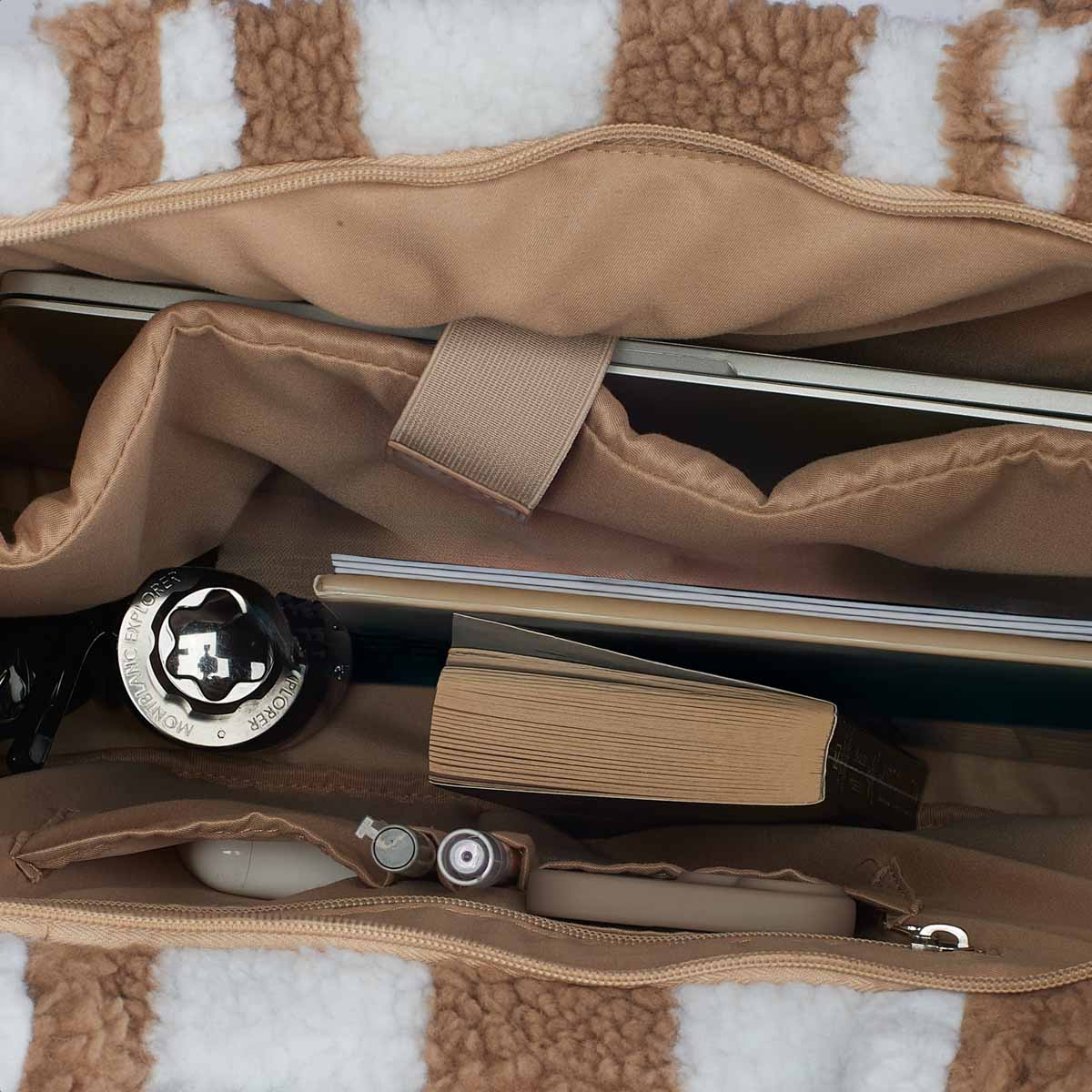 A tote bag filled with items: a laptop, book, pen, headphones, and a Montblanc pen case.