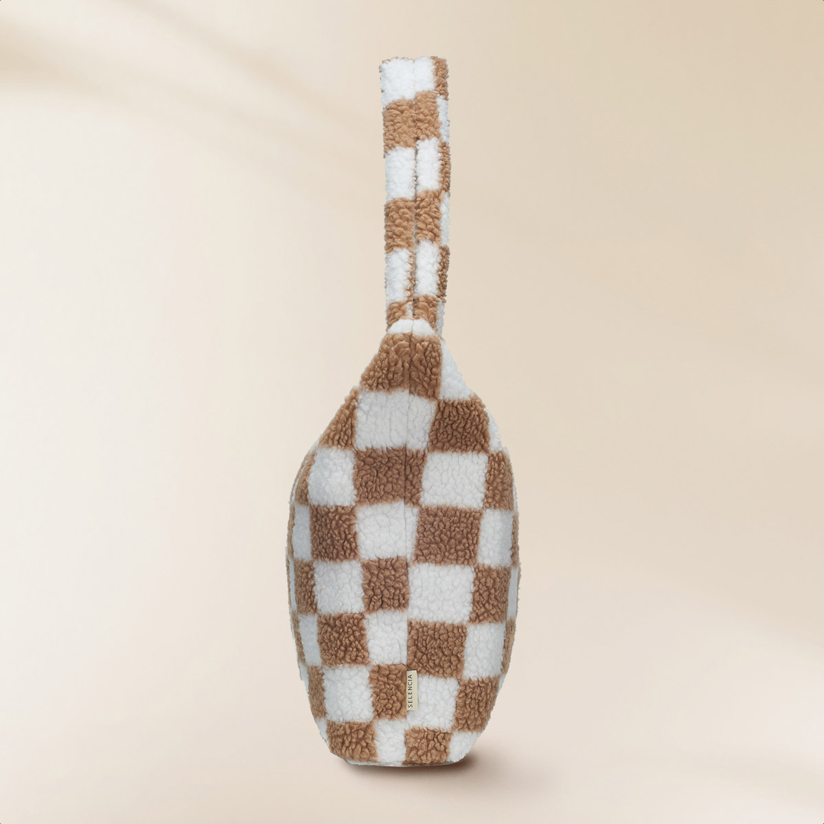 Tote bag with a brown and white checkered pattern. It has a matching handle and label.