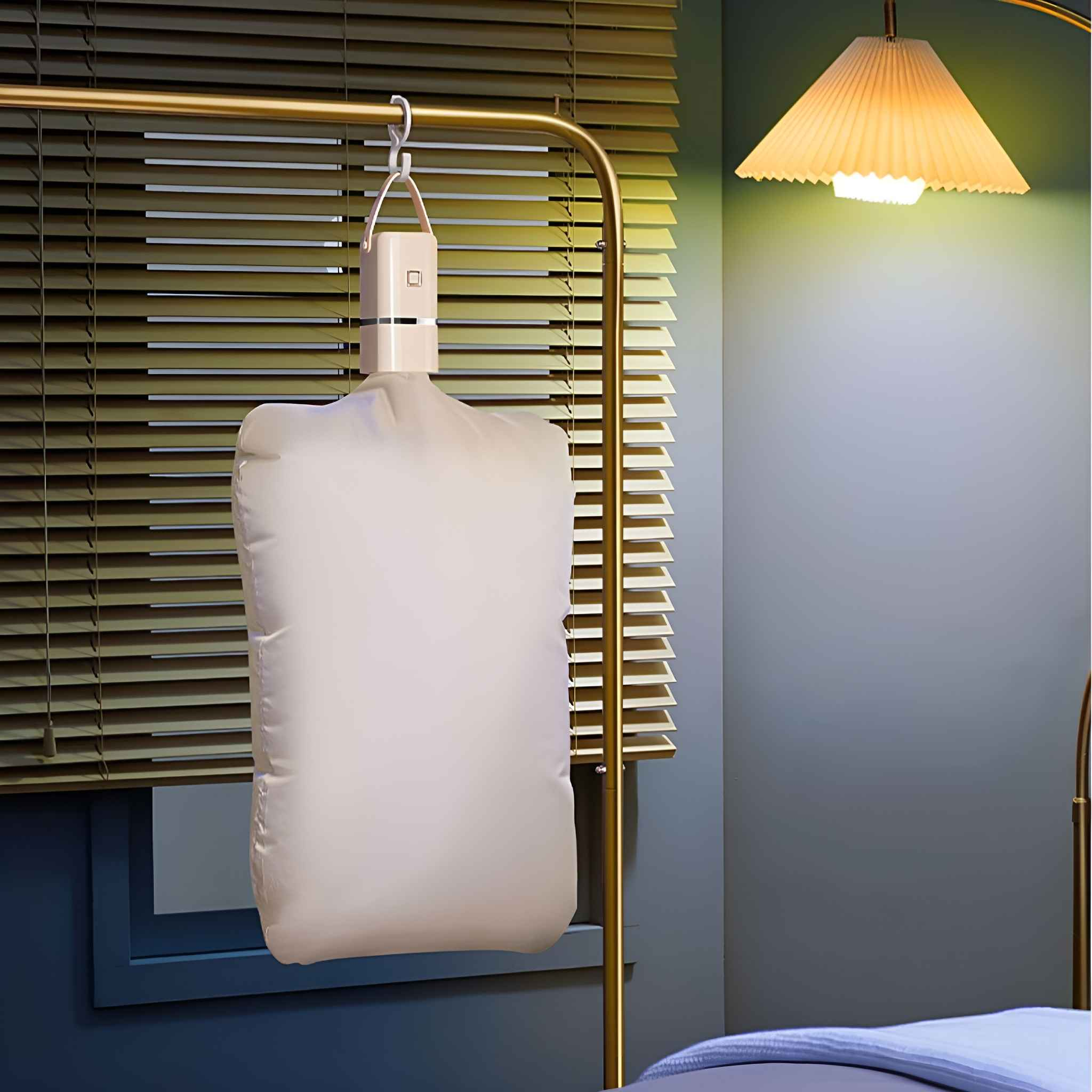 Ein weißer Wäschetrocknerbeutel, der an einer goldenen Stange hängt. Rechts ist eine Stehlampe.