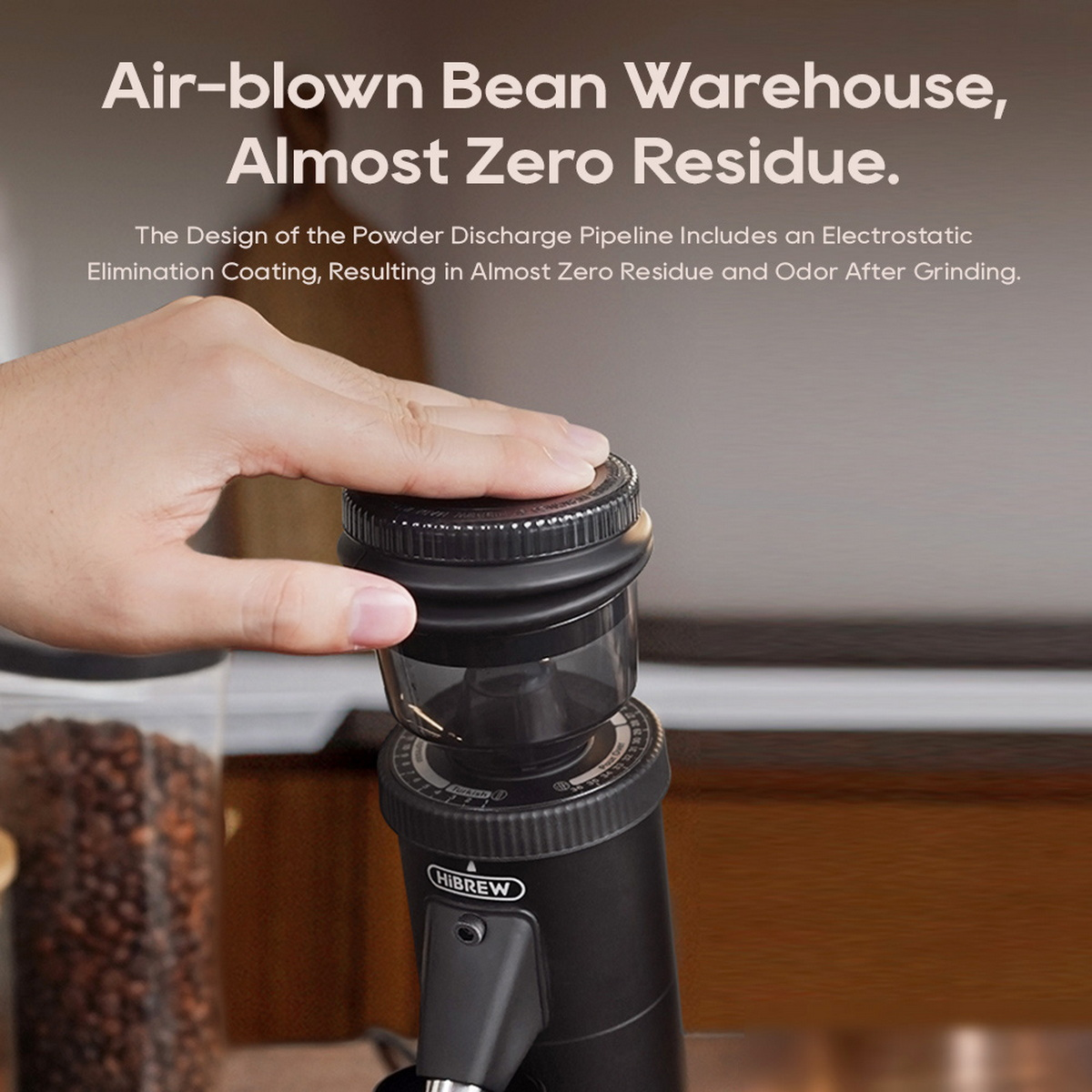 Ręka nad czarnym młynkiem do kawy. Tekst: 'Air-blown Bean Warehouse, Almost Zero Residue'.