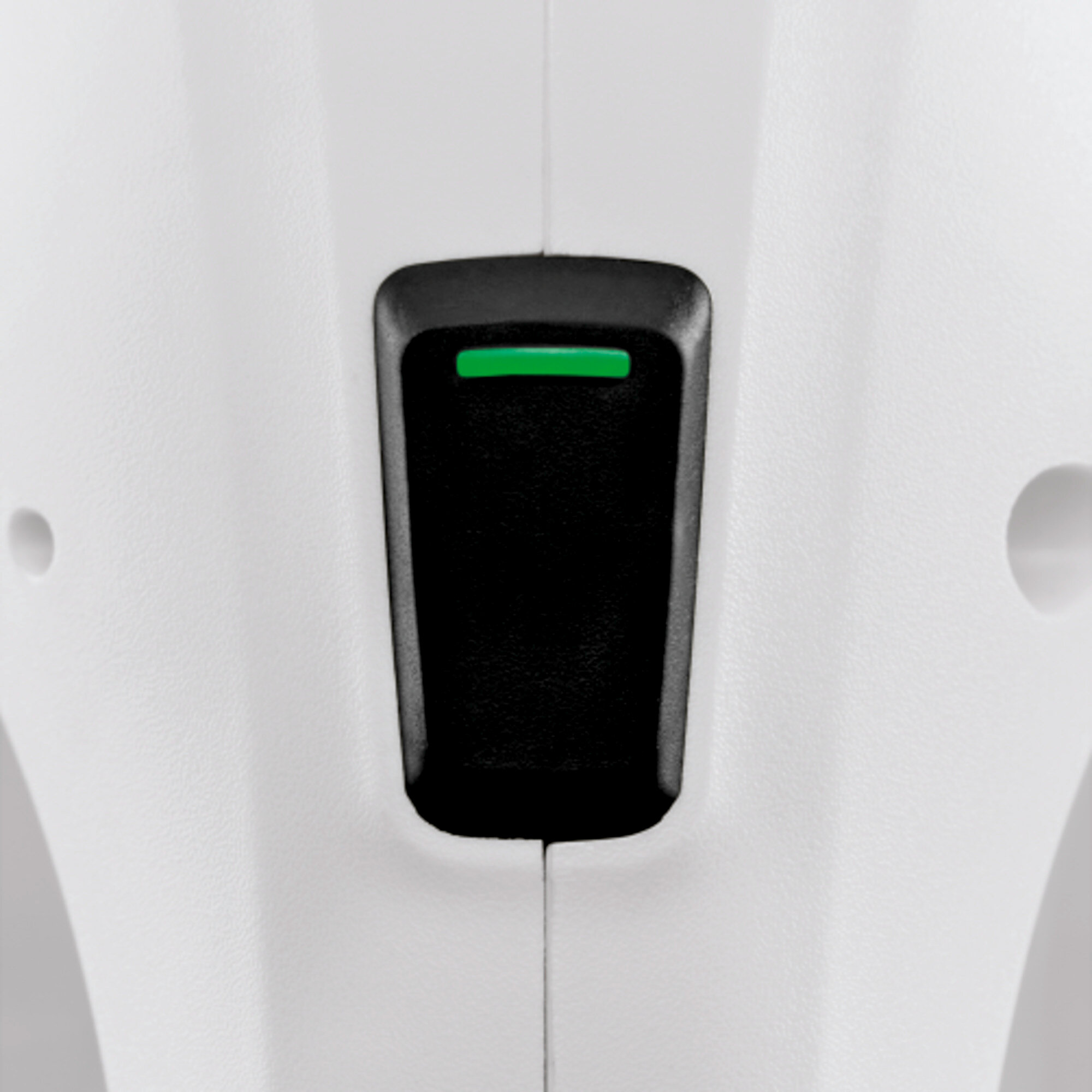 Close-up van een zwarte aan/uit-knop met een groen lampje op een witte achtergrond. De knop is verzonken.