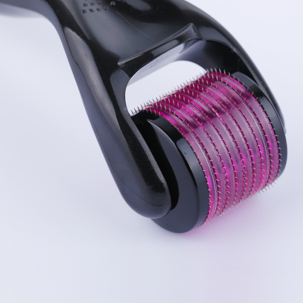 Nahaufnahme eines schwarzen Derma-Rollers mit lila Rolle. Weißer Hintergrund. Fokus auf die Rolle.