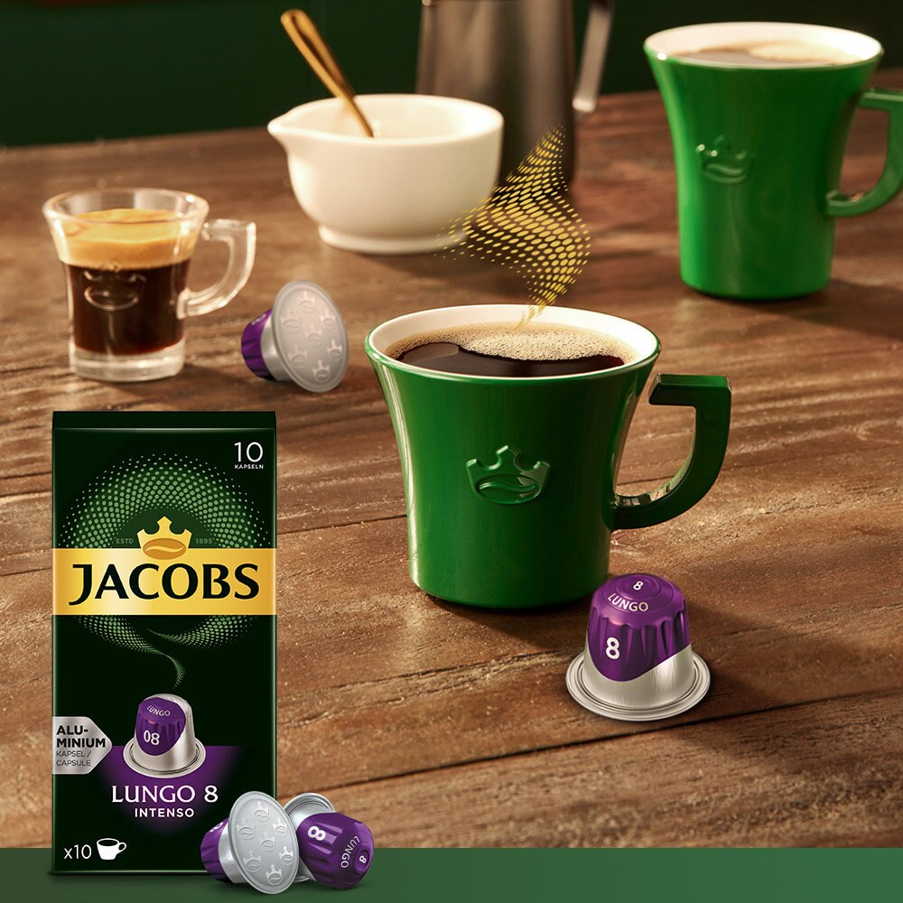 Jacobs Kaffee mit grünen Tassen und Kaffeebohnen. Eine Kaffeetasse wird mit Kaffee gefüllt.