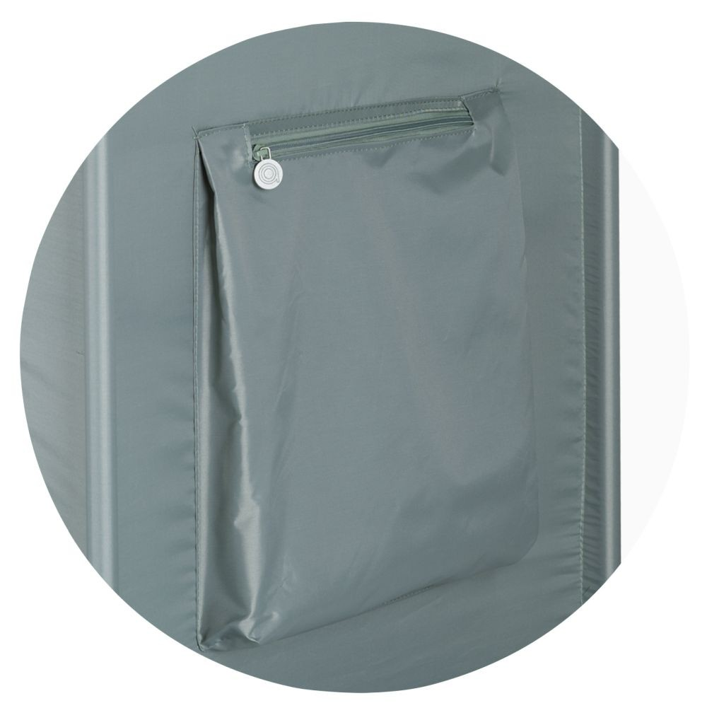 Nahaufnahme einer grauen Tasche auf einer grauen Oberfläche. Sie hat einen Reißverschluss und einen kleinen Metallkreis.