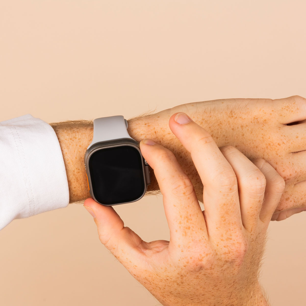 Man's wrist with a watch. He is touching the watch screen with his finger.