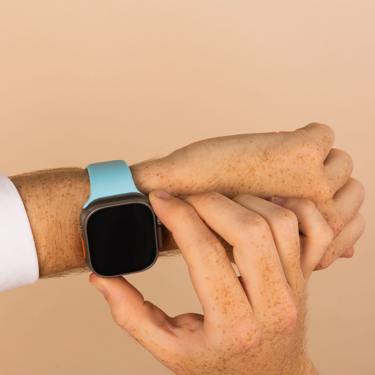 Man's wrist with a watch. He is touching the watch screen with his finger.
