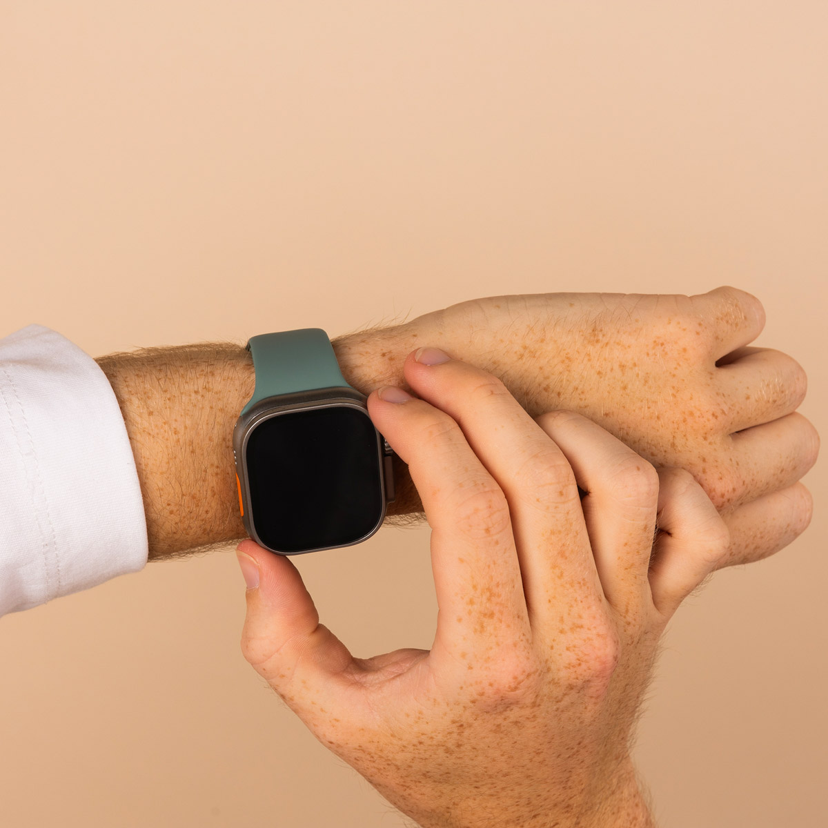 A hand with freckles wearing a smartwatch with a teal strap.