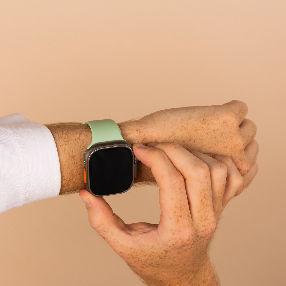 A hand with freckles wearing a smartwatch with a mint-green strap.