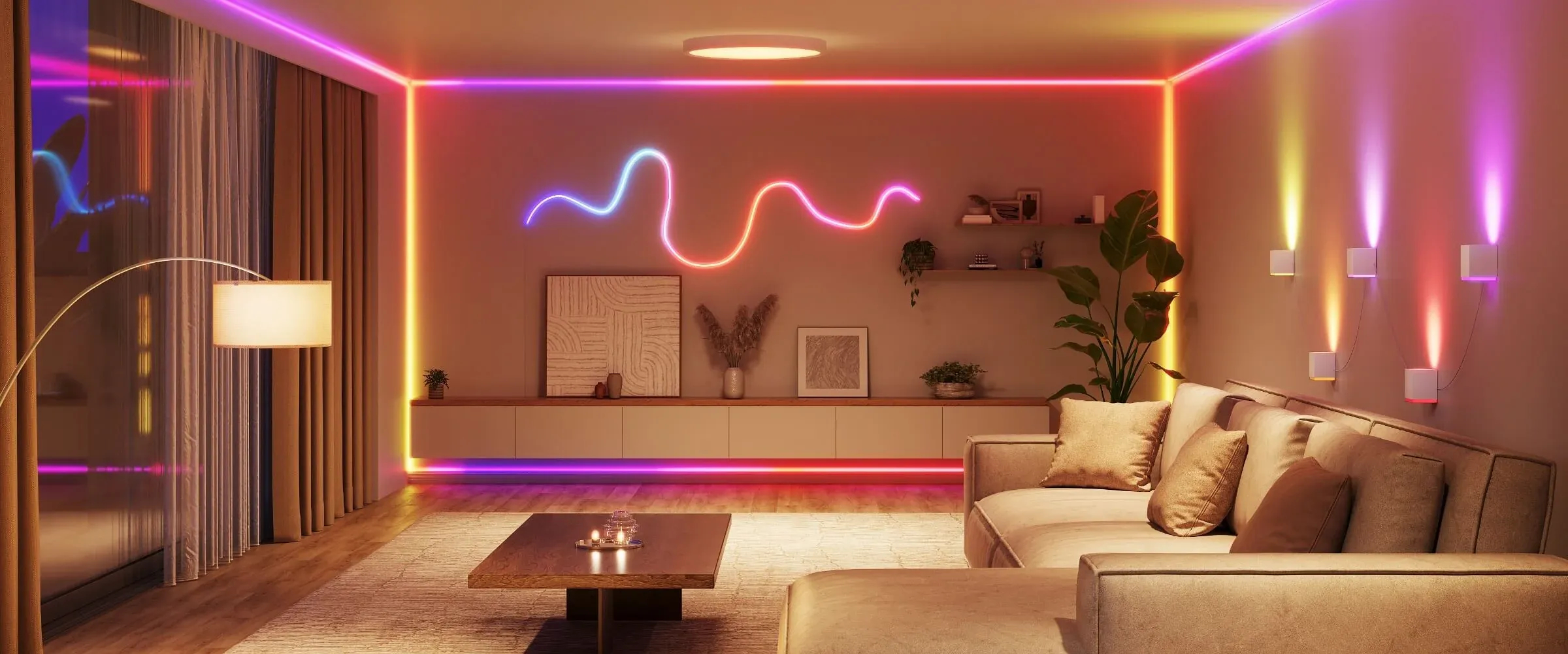 Soggiorno con divano, tavolo e illuminazione a LED colorata lungo il soffitto e le pareti. Una lampada è accesa.