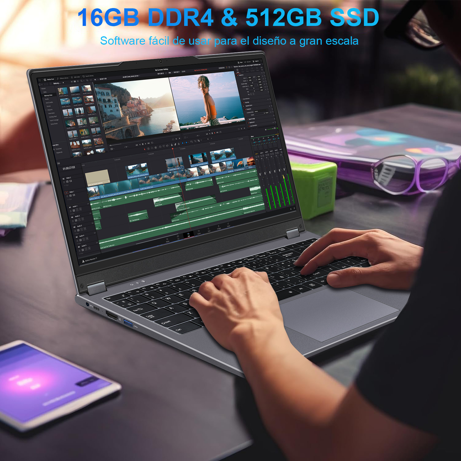 Un portátil que muestra software de edición de video, con las manos en el teclado. Una tableta en la esquina.
