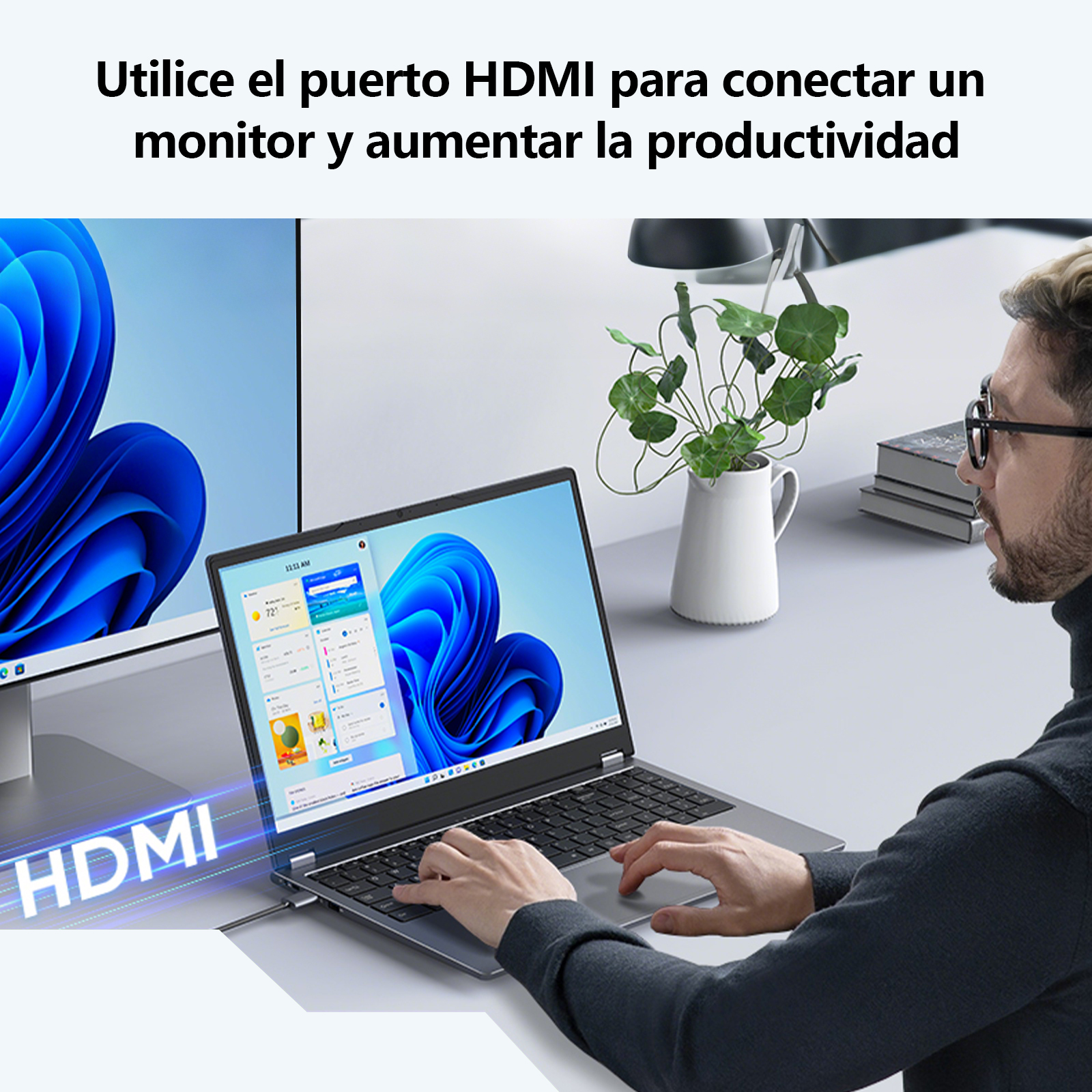 Un hombre trabajando en un portátil. Hay un monitor a la izquierda. Hay una planta a la derecha.