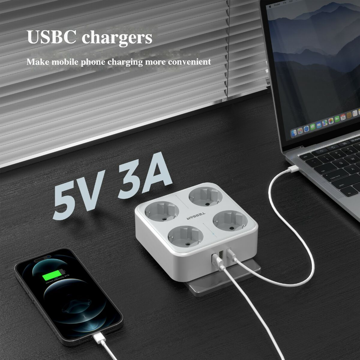Una regleta blanca cargando un teléfono y una computadora portátil en un escritorio negro. La regleta tiene puertos USB.