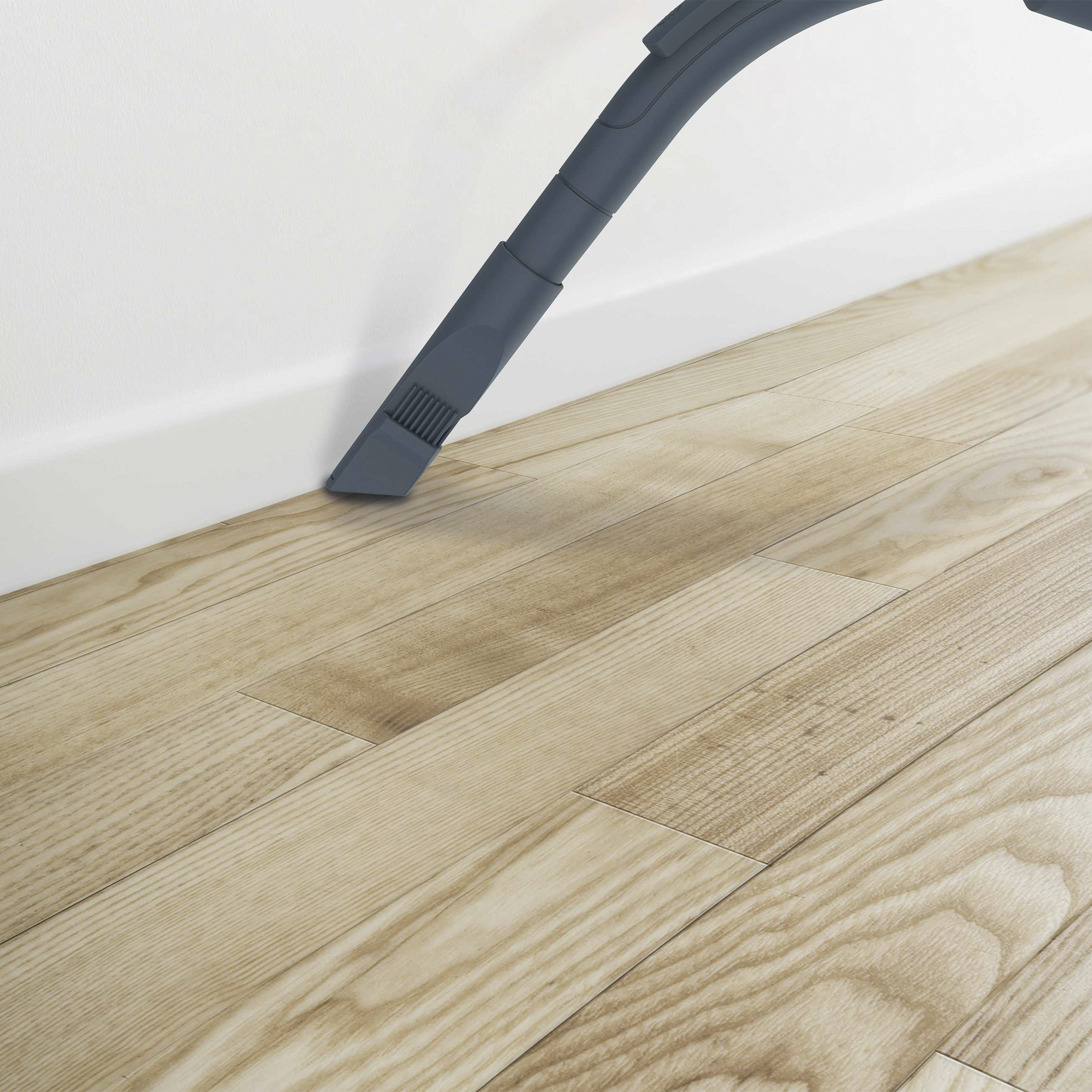 Głowica odkurzacza czyszcząca drewnianą podłogę obok białej ściany.