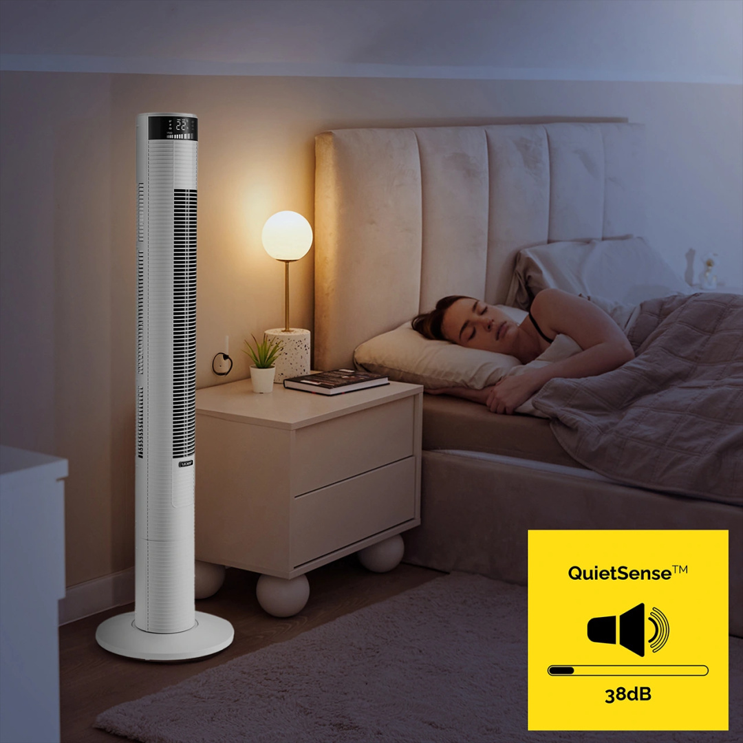 Wentylator wieżowy w sypialni. Kobieta śpi. Lampa i szafka nocna znajdują się obok wentylatora.