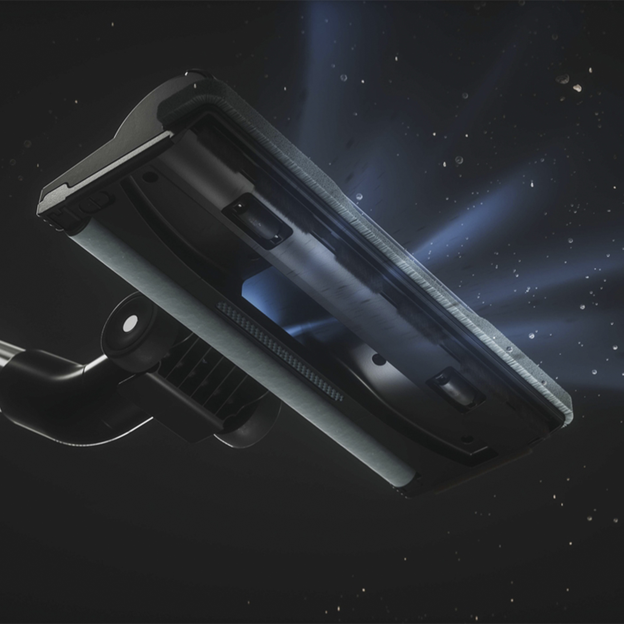 Głowica odkurzacza jest pokazana podczas czyszczenia i emitowania wiązek światła. Tło jest ciemne.