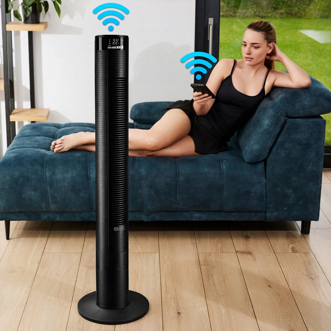 Kobieta na niebieskiej kanapie używająca telefonu w pobliżu czarnego wentylatora wieżowego z symbolami Wi-Fi.