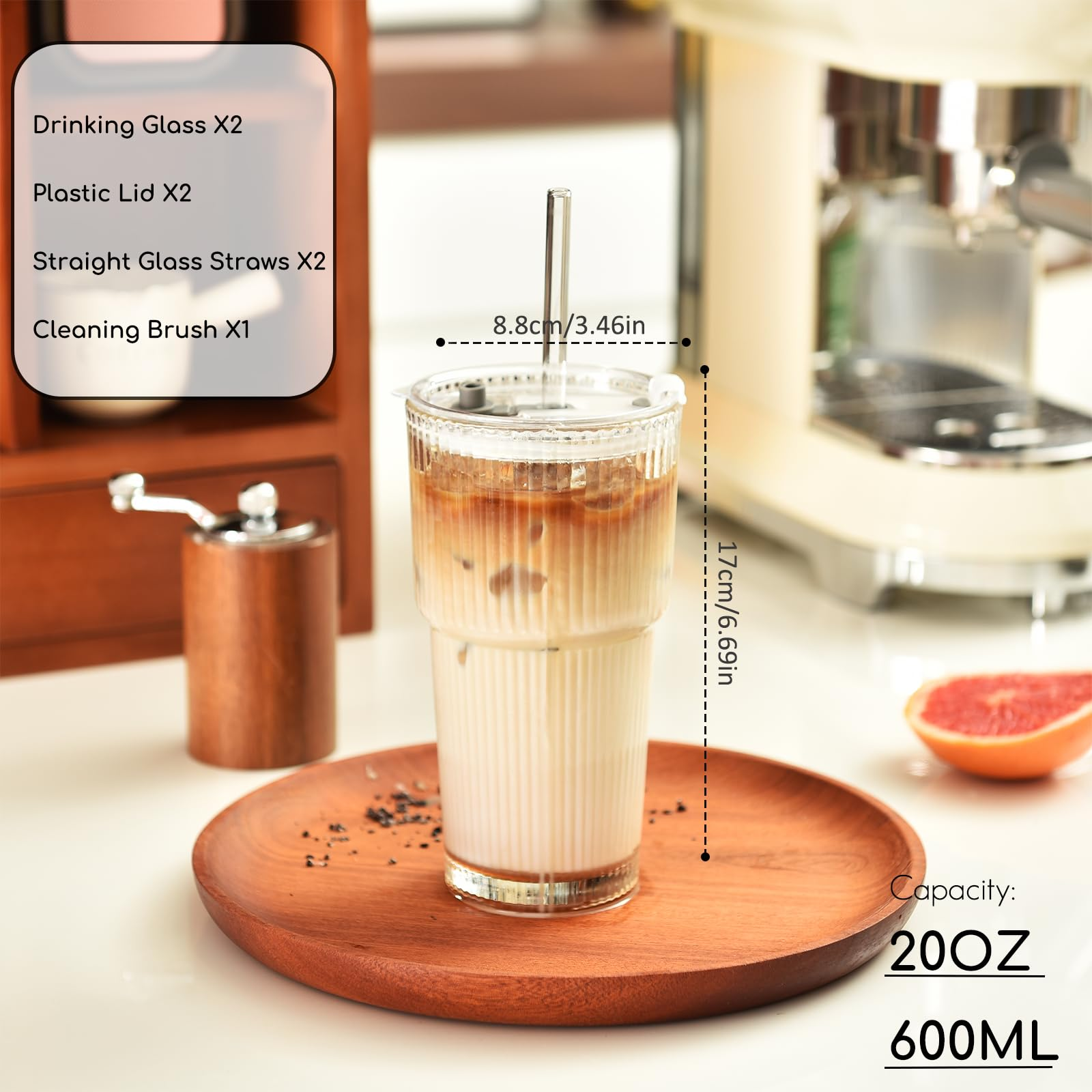 Ein großes Glas Kaffee mit Eis und einem Strohhalm. Ein Holztablett und eine Kaffeemühle sind ebenfalls sichtbar.