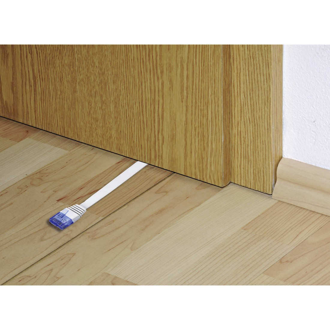 Cavo di rete bianco sotto una porta, con connettore blu a sinistra. Pavimento e porta in legno.
