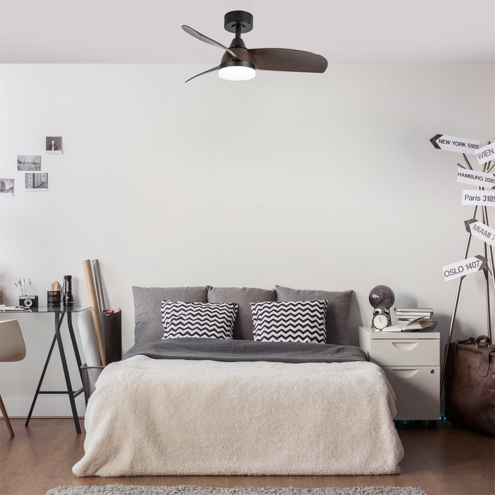 Un dormitorio con un ventilador de techo sobre una cama, un escritorio y una señal.