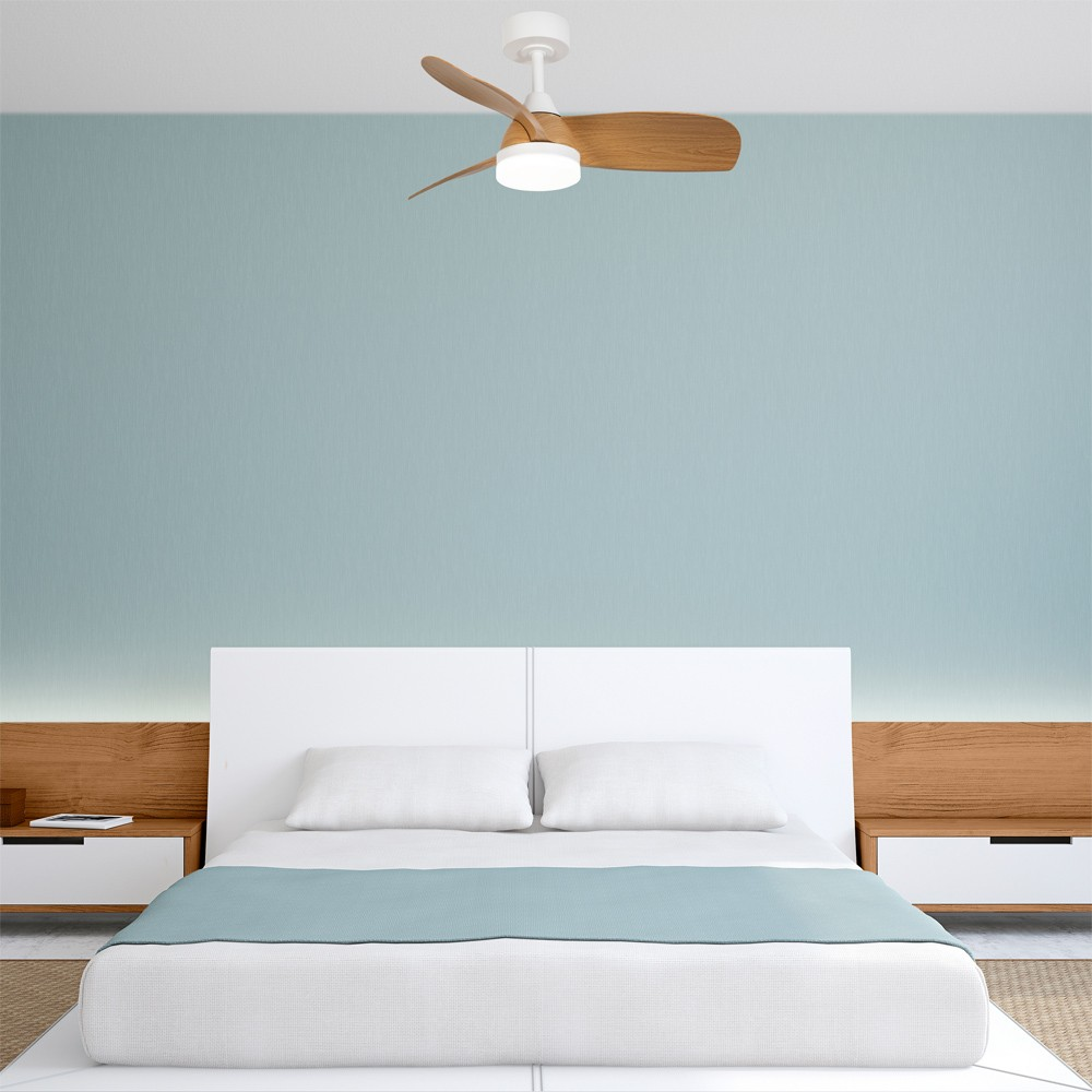 Un dormitorio con cama, mesitas de noche y ventilador de techo. La pared es azul claro.