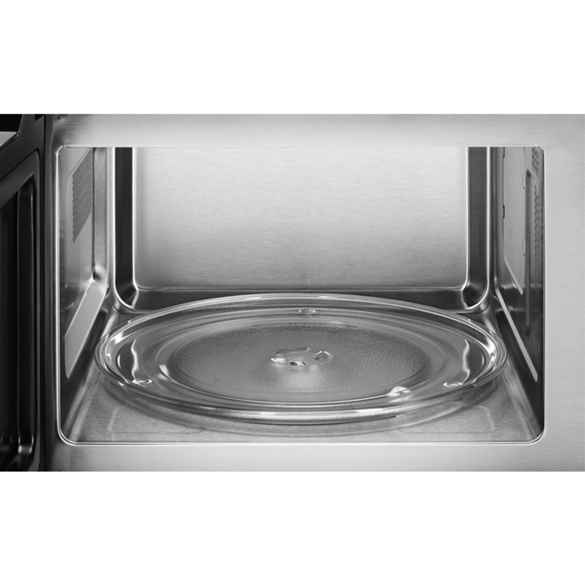 Widok wnętrza kuchenki mikrofalowej. Przezroczysta szklana płyta znajduje się wewnątrz ze stali nierdzewnej. Szklana płyta jest wyśrodkowana.