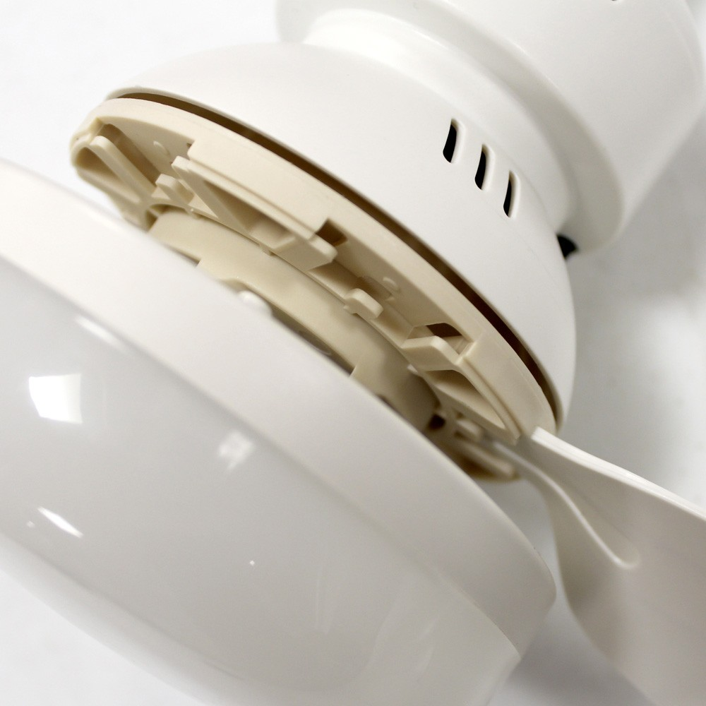 Primer plano de la base de un ventilador de techo blanco y beige, que muestra los detalles de la luz y el motor.