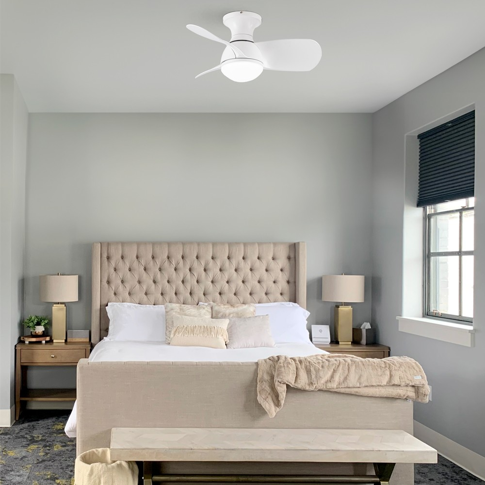 Dormitorio con cama con cabecero beige acolchado, dos lámparas y ventilador de techo blanco. La habitación tiene una ventana.