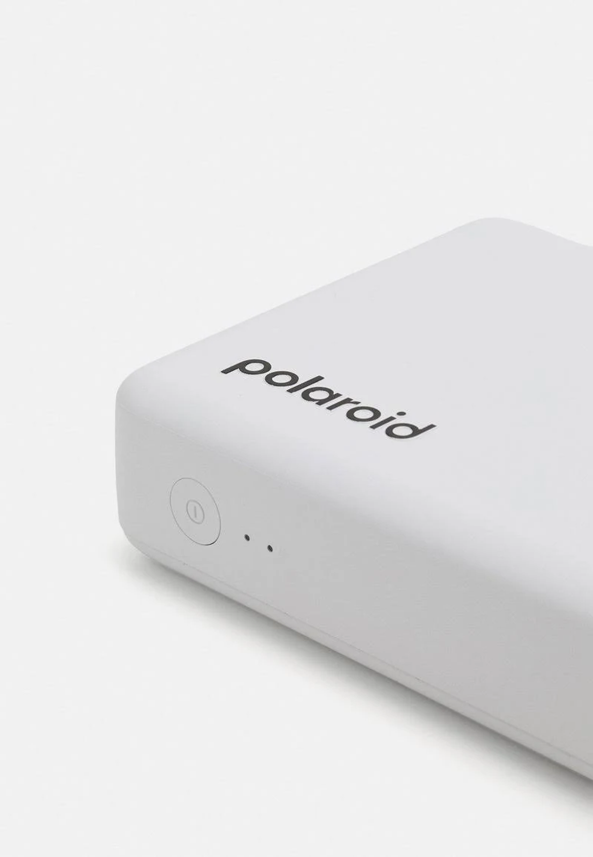 Ein weißes Polaroid-Gerät mit aufgedrucktem Markennamen auf einer weißen Oberfläche.