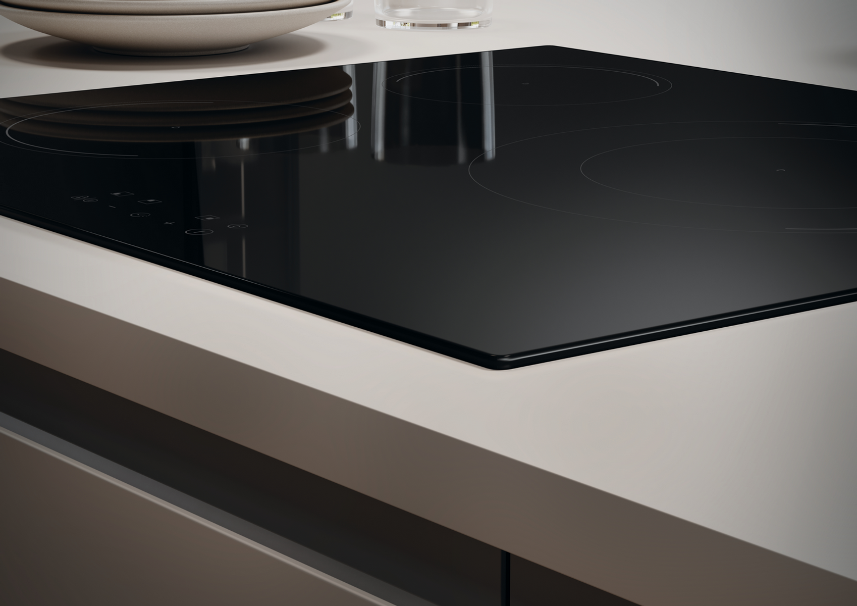 Czarna płyta indukcyjna na jasnym blacie, z białym talerzem i szklanką.