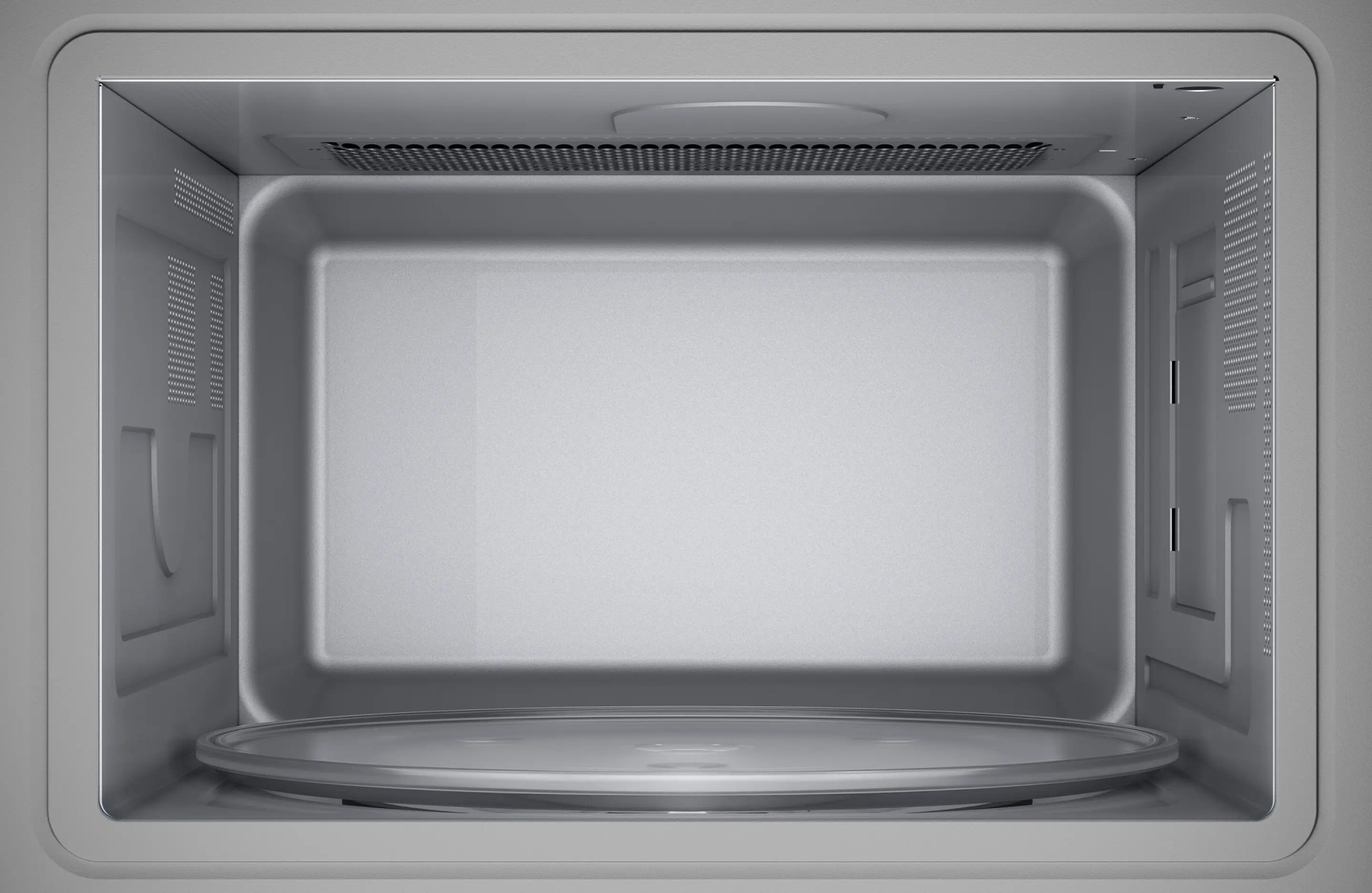 Puste, srebrne wnętrze kuchenki mikrofalowej ze szklaną płytą, szarą ramą i otworami wentylacyjnymi.