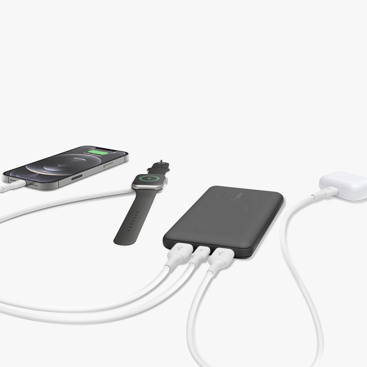 Power bank Belkin nero che carica telefono, orologio e auricolari con cavi bianchi.