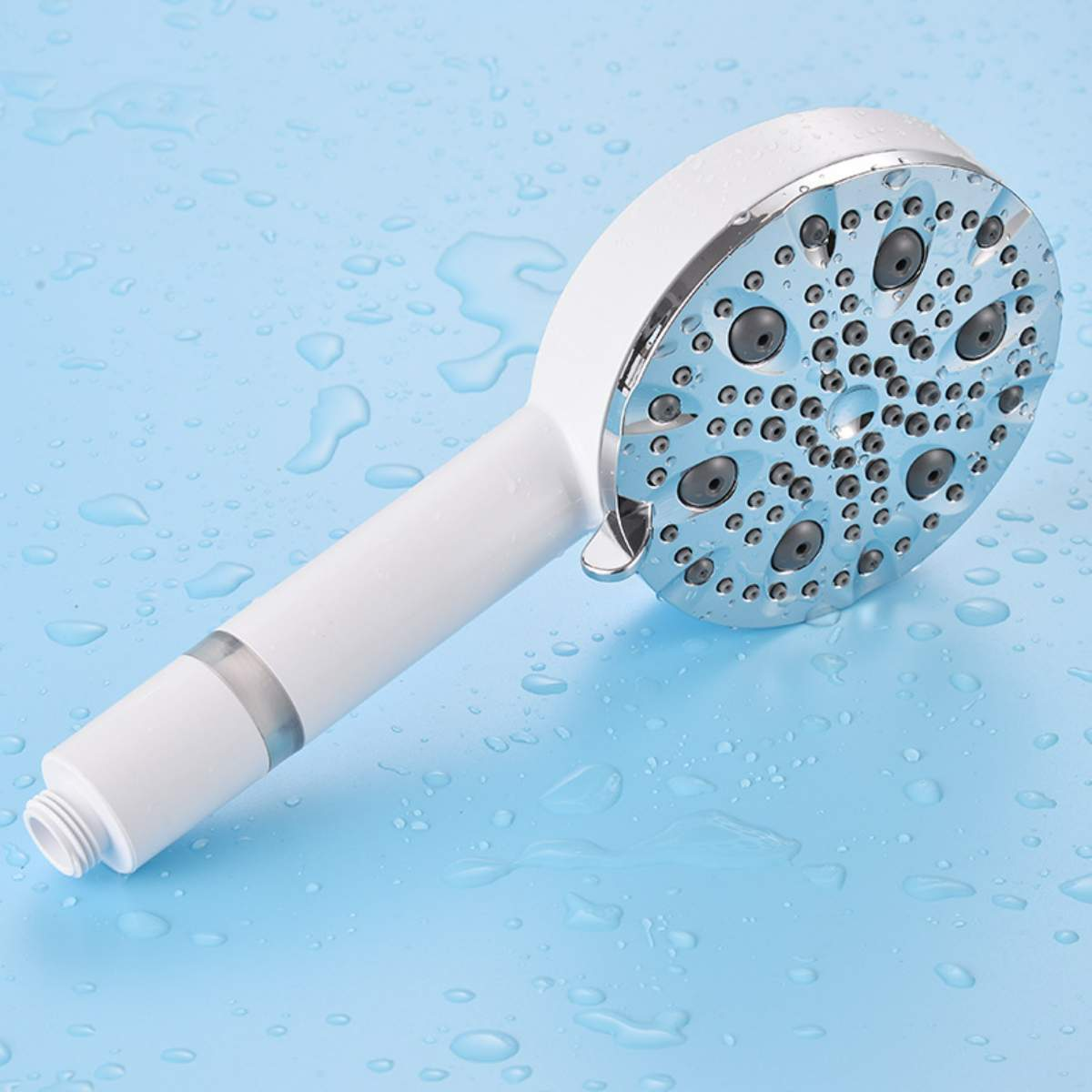 Ein weißer Duschkopf mit Chromdetails, der Wasser auf eine blaue Oberfläche mit Wassertropfen sprüht.