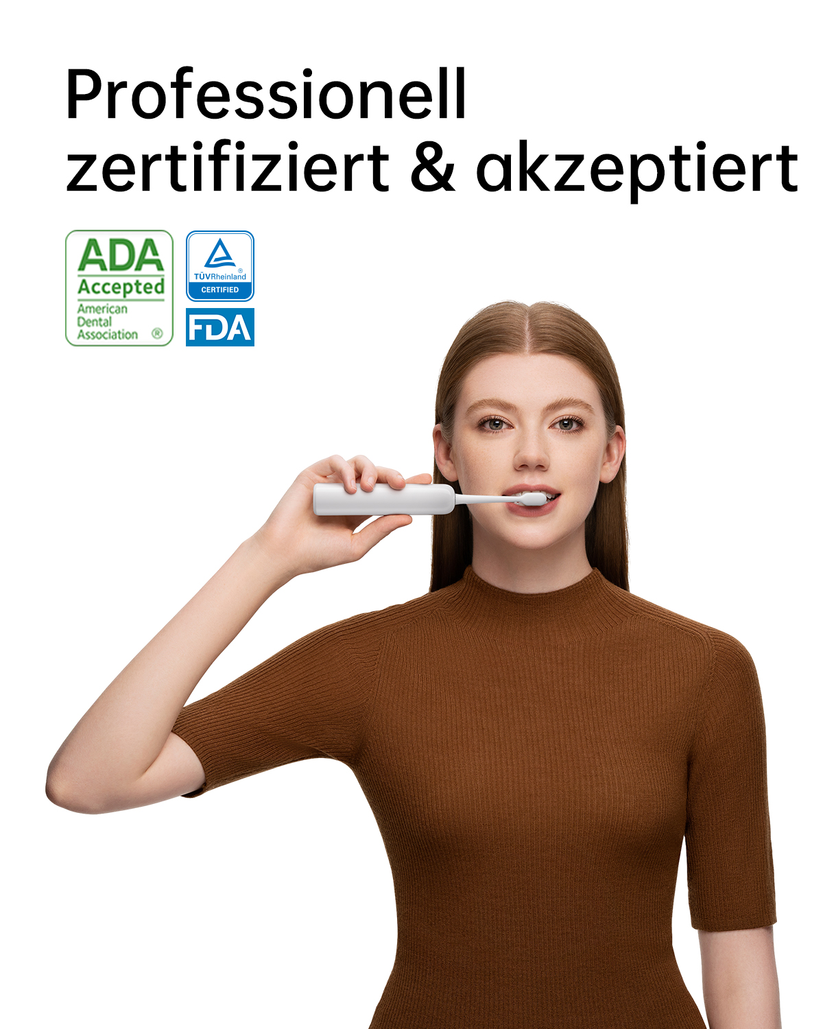 Eine Frau hält eine elektrische Zahnbürste, zertifiziert von ADA, TÜV und FDA, und lächelt in die Kamera.