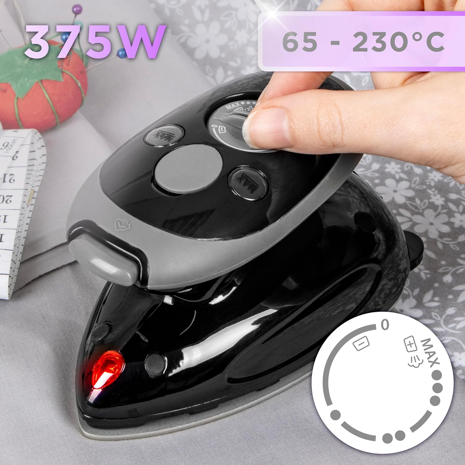 Schwarzes Bügeleisen mit einer Hand, die einen Drehregler einstellt. Stoffhintergrund mit Nähzubehör und Maßband.