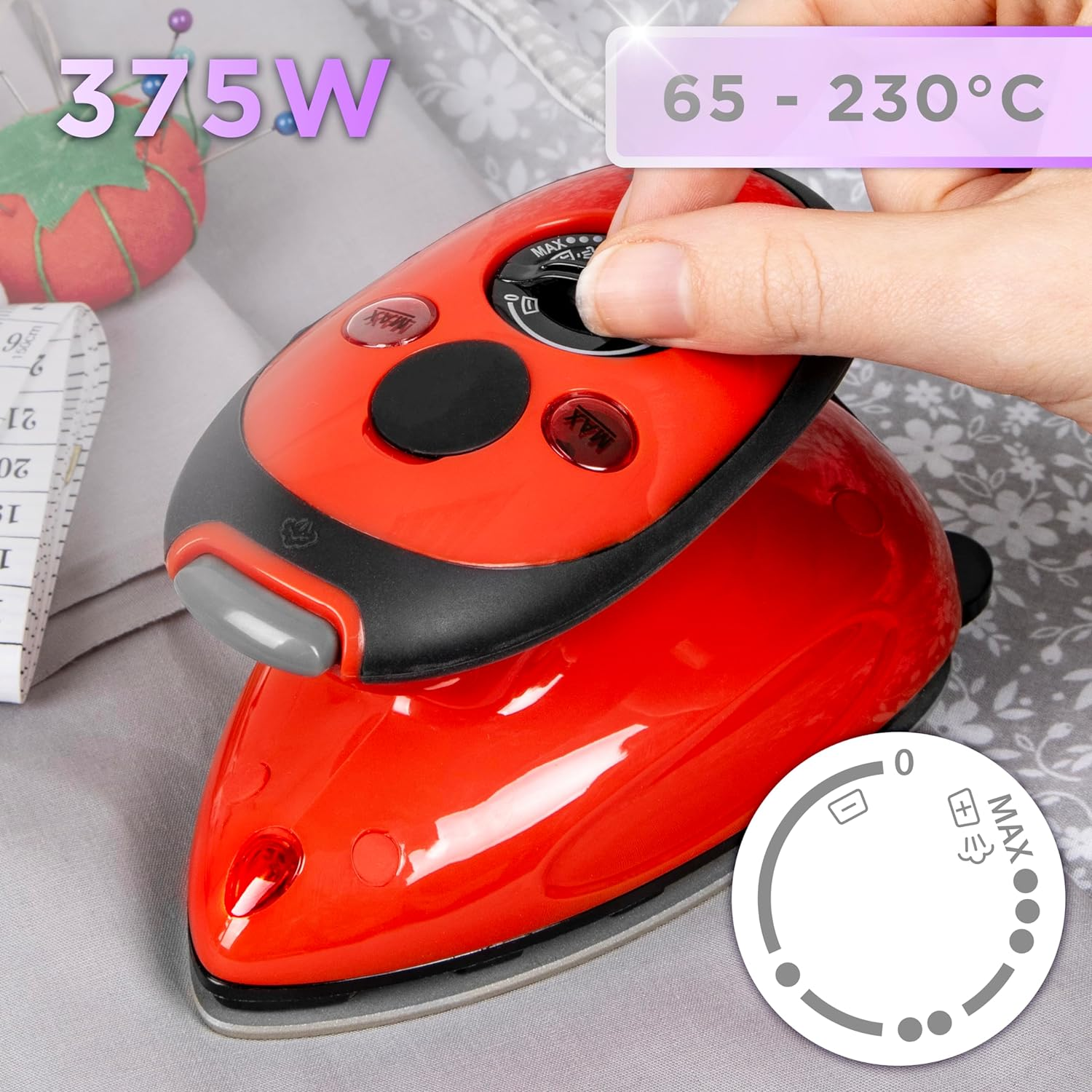 Rotes Bügeleisen mit einer Hand, die den Temperaturregler einstellt, Stoffhintergrund mit Nähutensilien und Waage.