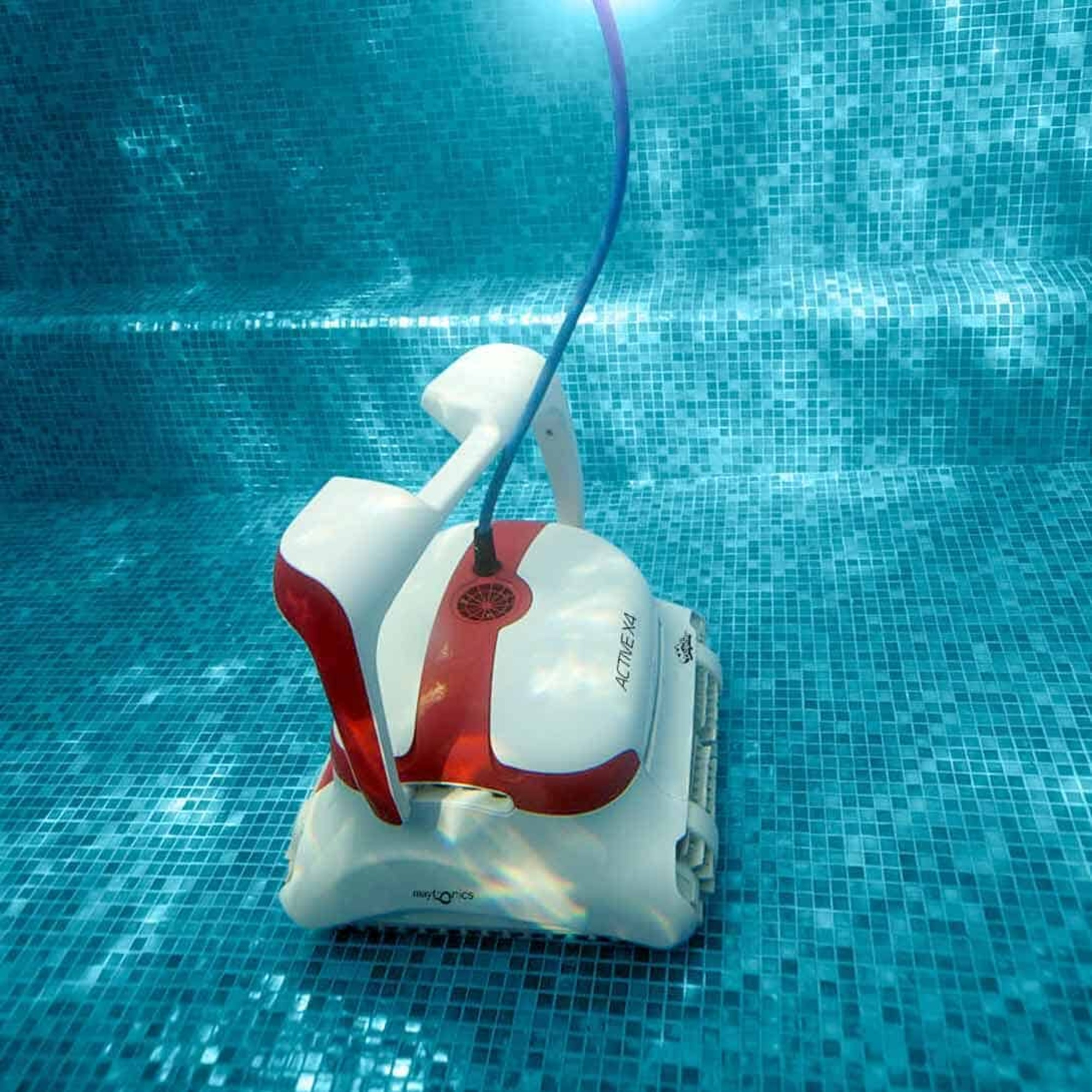 Limpiador de piscina blanco y rojo bajo el agua. Está en ángulo hacia la cámara, en una piscina con azulejos.
