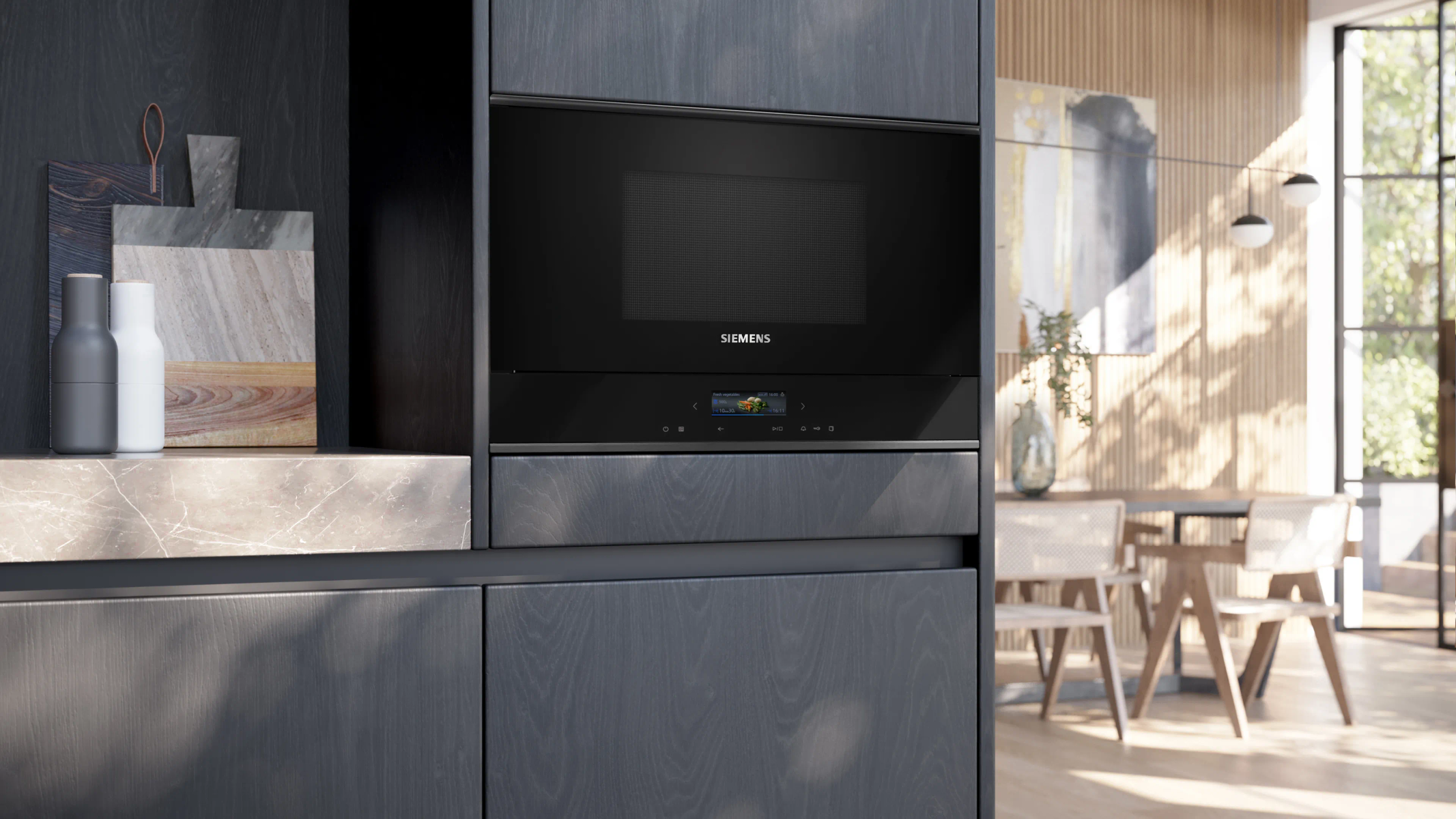 Kuchenka mikrofalowa Siemens wbudowana w ciemną drewnianą szafkę w nowoczesnej, jasnej kuchni.