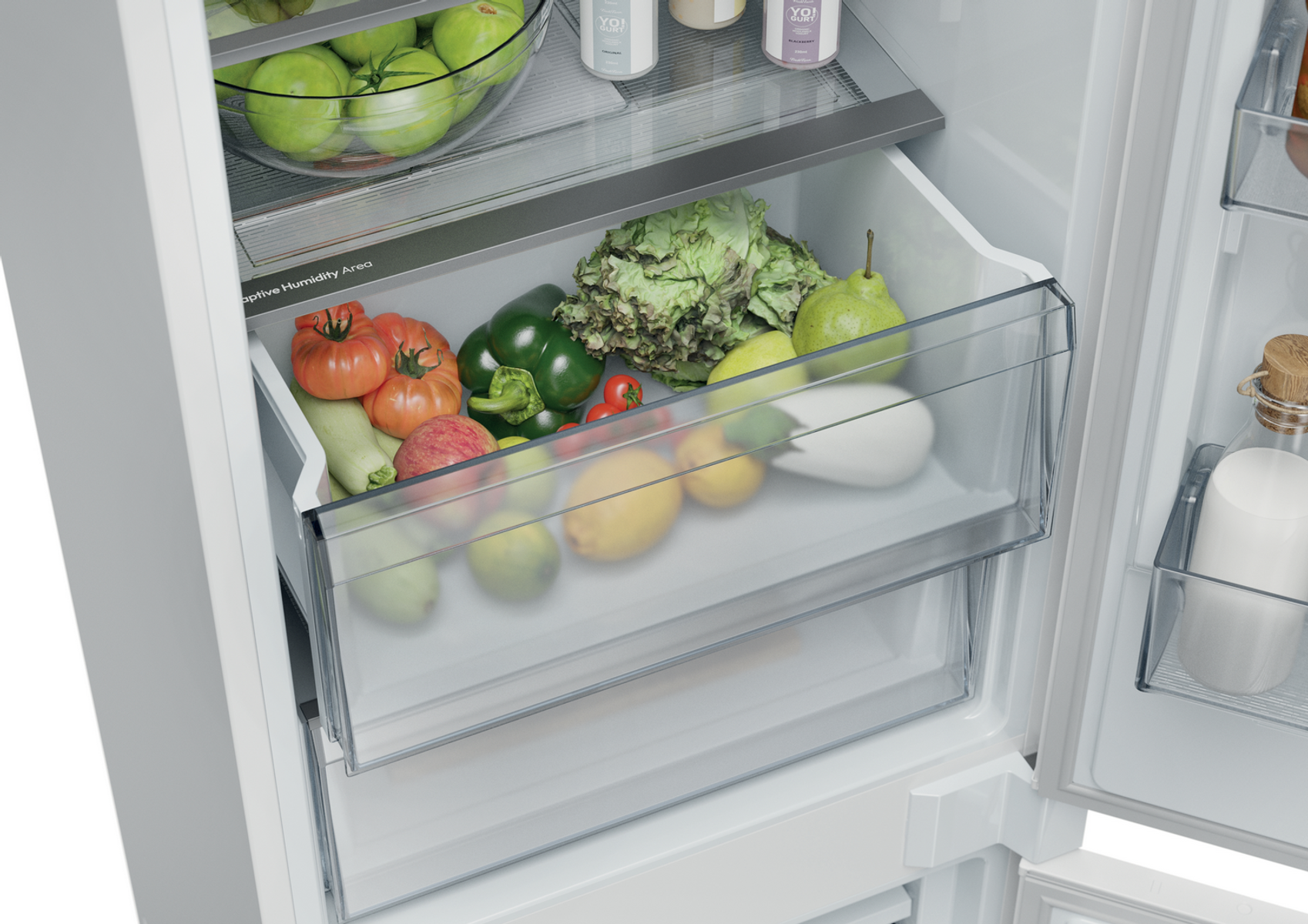 Wewnątrz lodówki znajduje się przezroczysta szuflada z świeżymi produktami, takimi jak pomidory, cytryny, bakłażany i sałata.