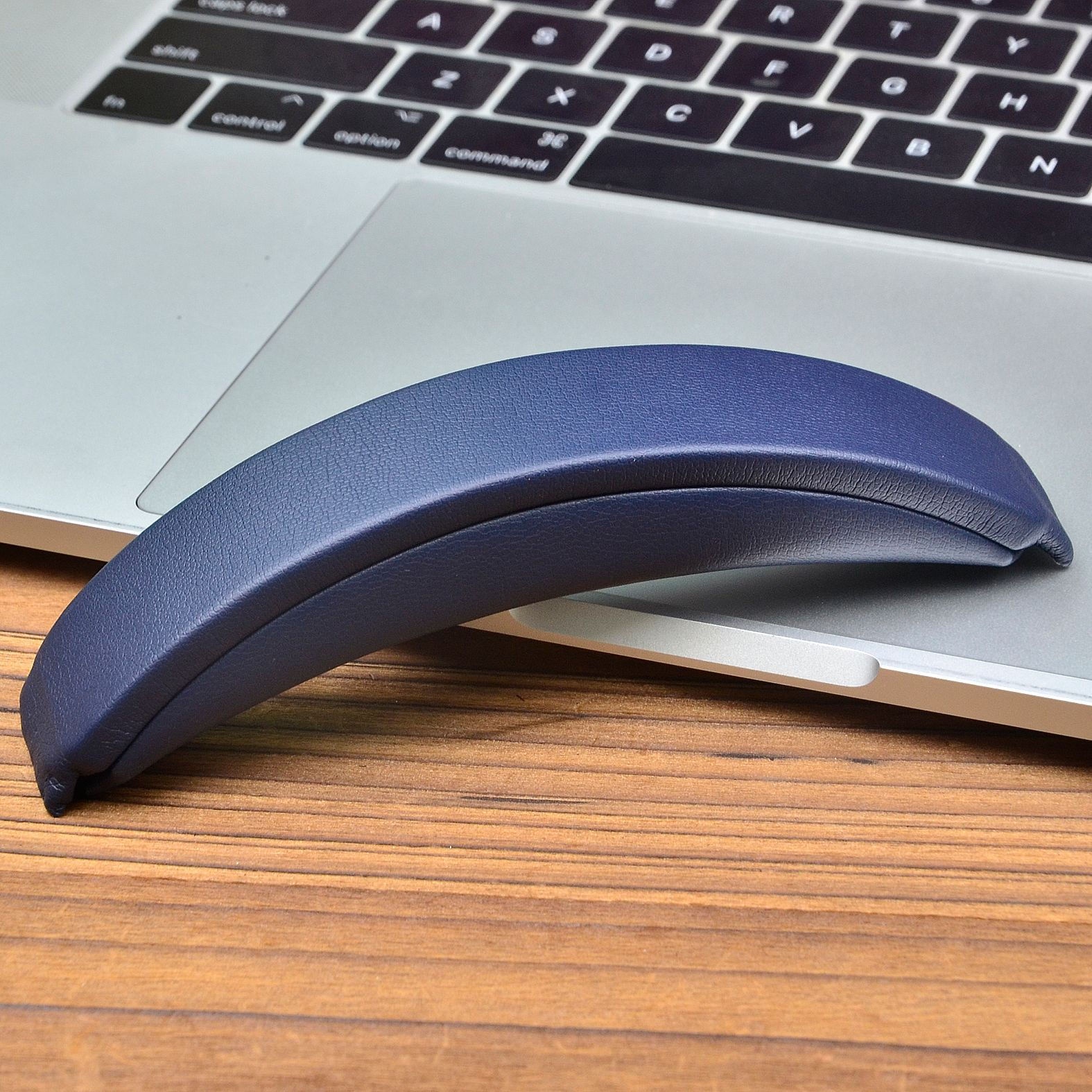 Un archetto blu per cuffie su una tastiera di un laptop, su un tavolo di legno.