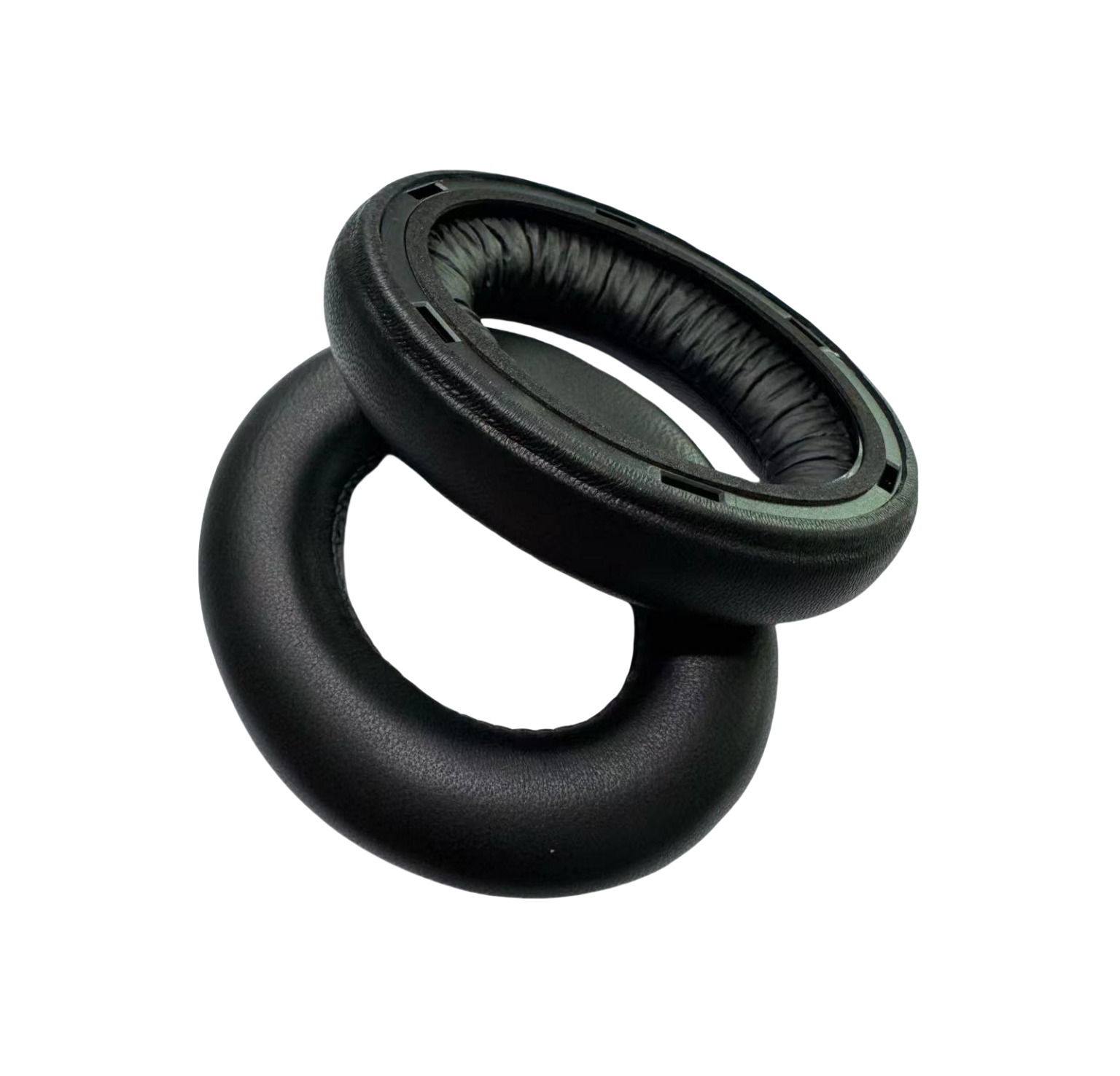 Due cuscinetti auricolari neri per cuffie, uno dentro l'altro, su sfondo bianco. Entrambi sono rotondi.