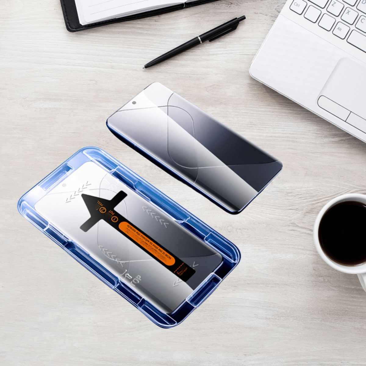 Una scena di scrivania con un telefono, protezione schermo in una cornice blu e una protezione separata. Sono visibili un laptop e un caffè.