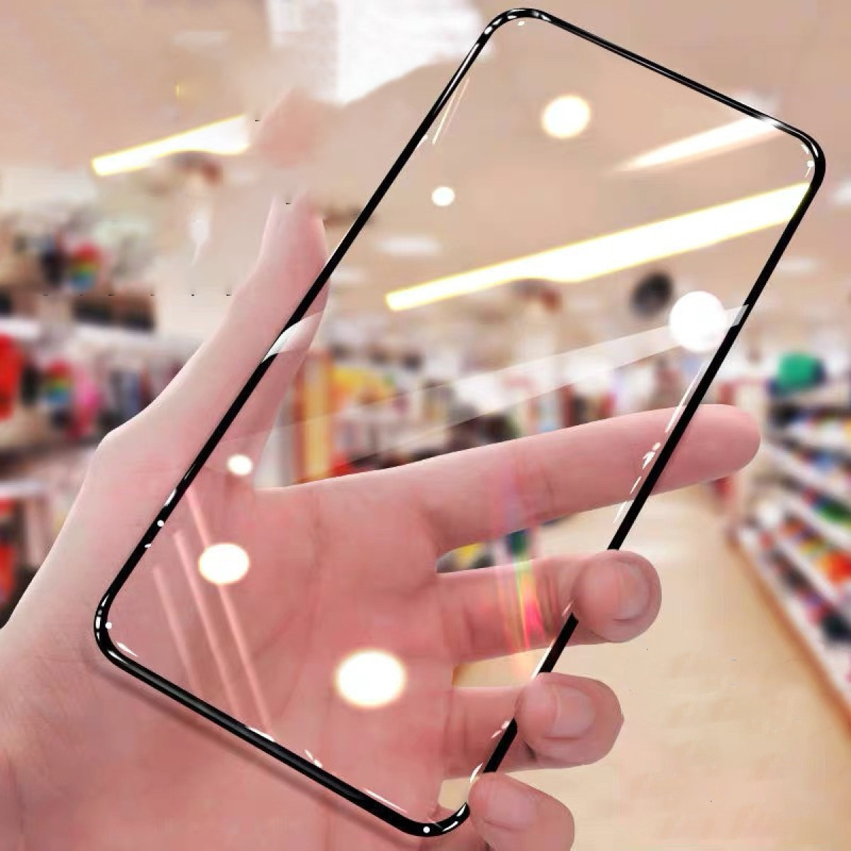 Eine Hand, die einen Displayschutz hält. Der Schutz ist klar mit schwarzem Rand. Der Hintergrund ist unscharf.