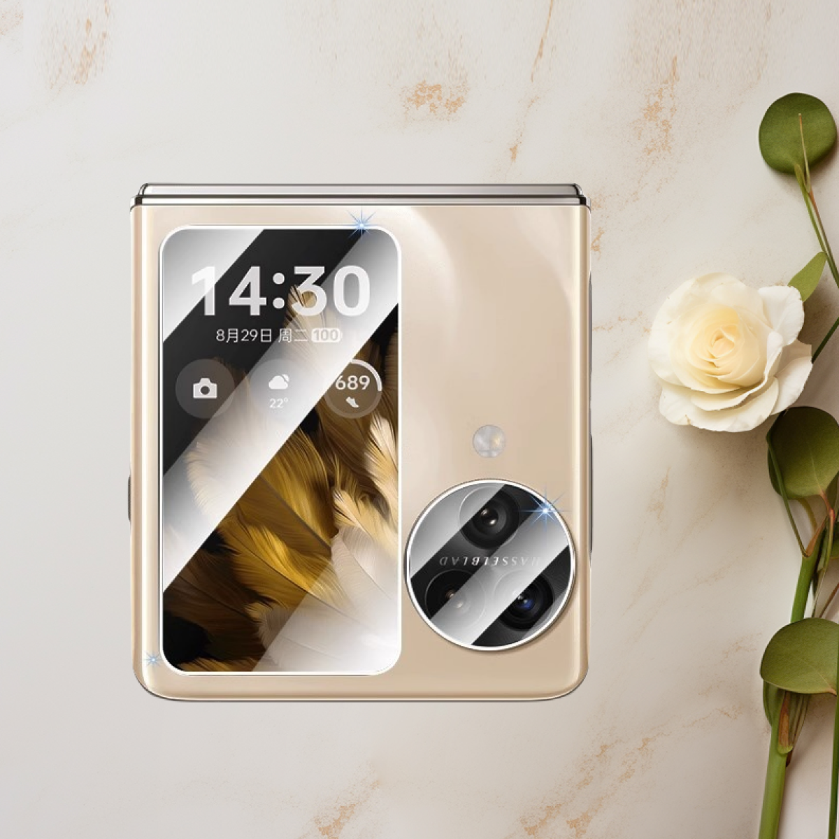 Telefono pieghevole dorato con protezione schermo che mostra l'ora. Rosa e foglie a destra su un tavolo chiaro.