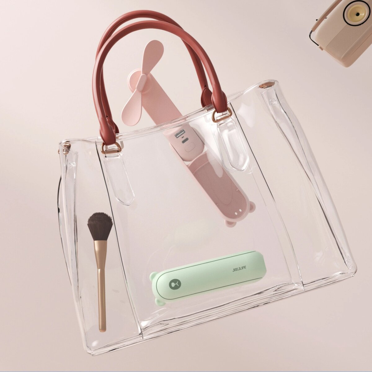 Transparente Handtasche mit einem kleinen rosa Ventilator, einem grünen Ventilator, einem Make-up-Pinsel und einem Radio. Alles in der Tasche.