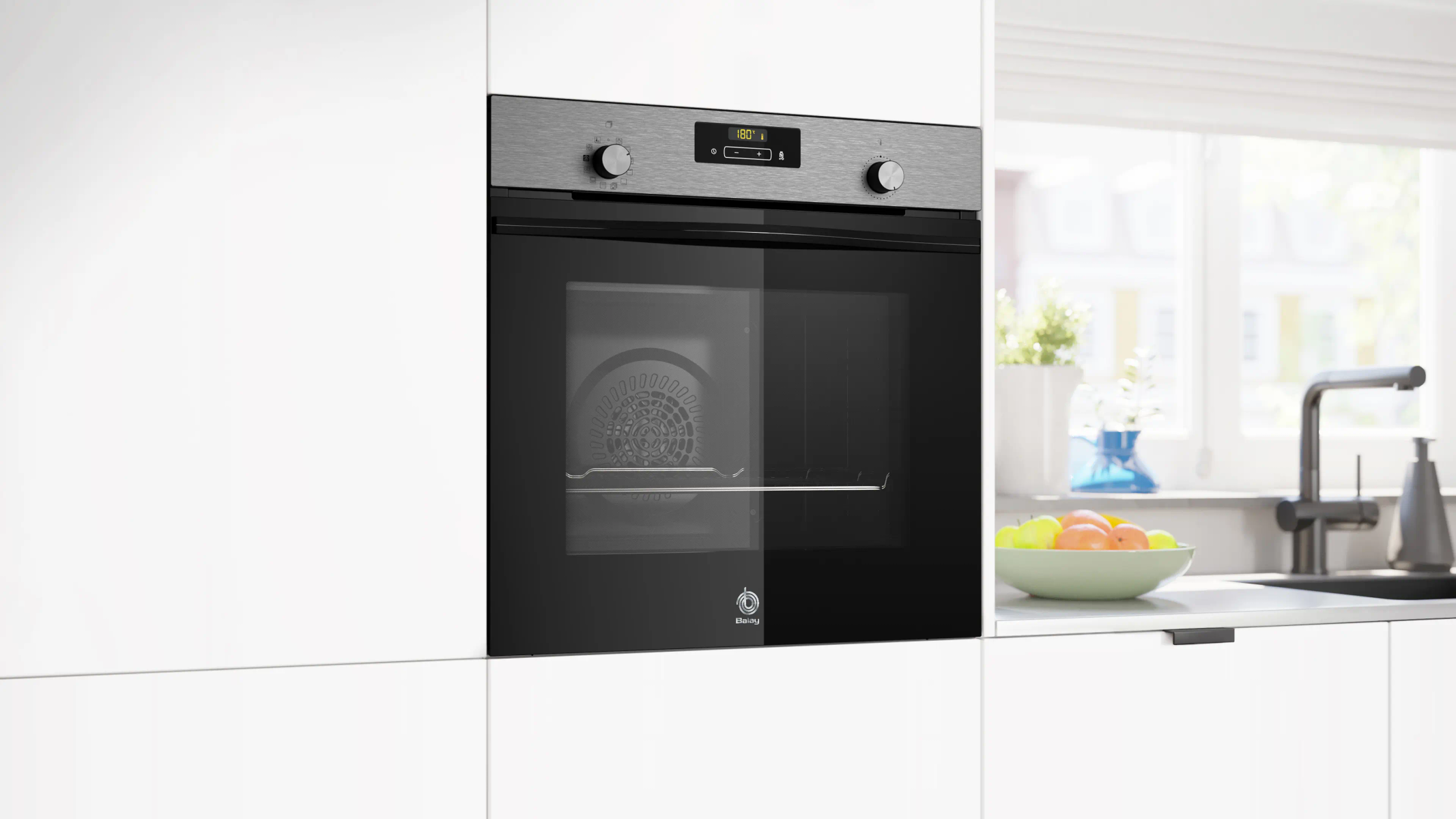 Czarny piekarnik do zabudowy jest zintegrowany z białymi szafkami kuchennymi, w pobliżu znajduje się misa na owoce i zlew.